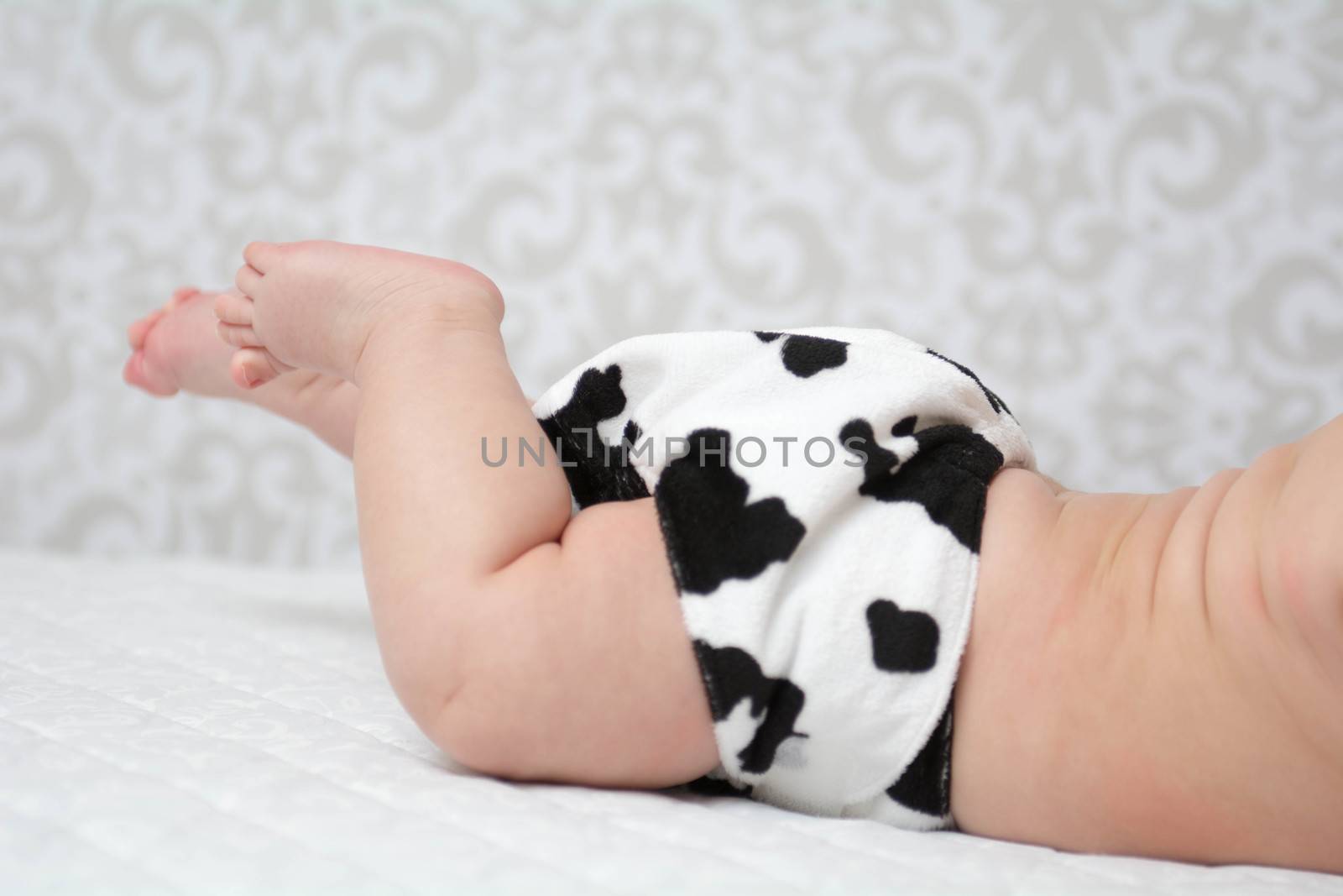 Baby laying on the belly wearing black & white reusable nappy