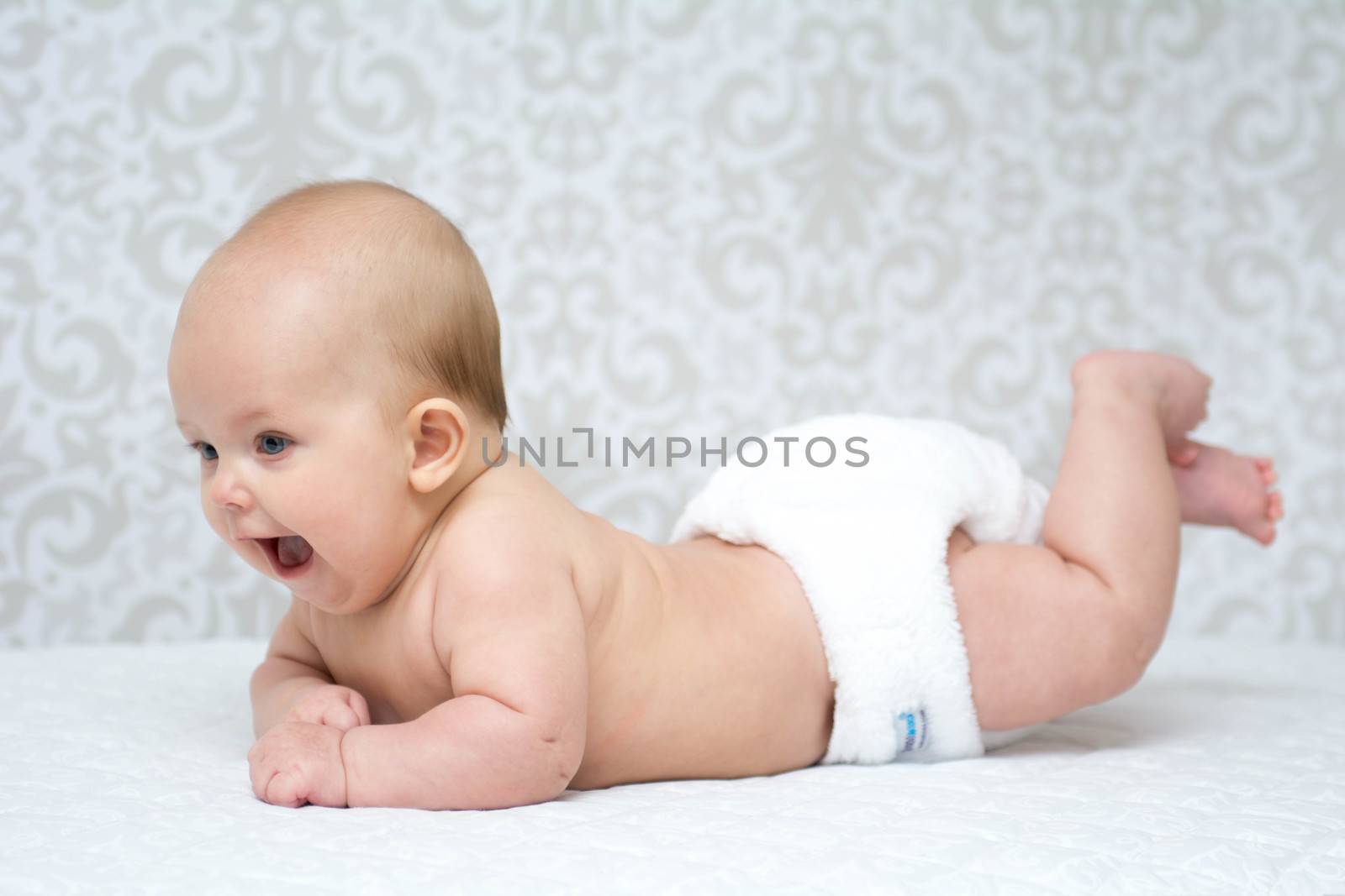 happy  baby lying on the belly wearing reusable nappy