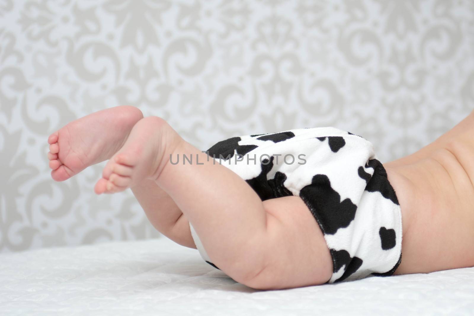 Baby laying on the belly wearing black & white reusable nappy