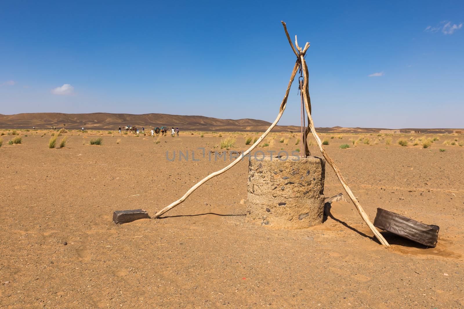 water well in the Sahara desert and the passing caravan