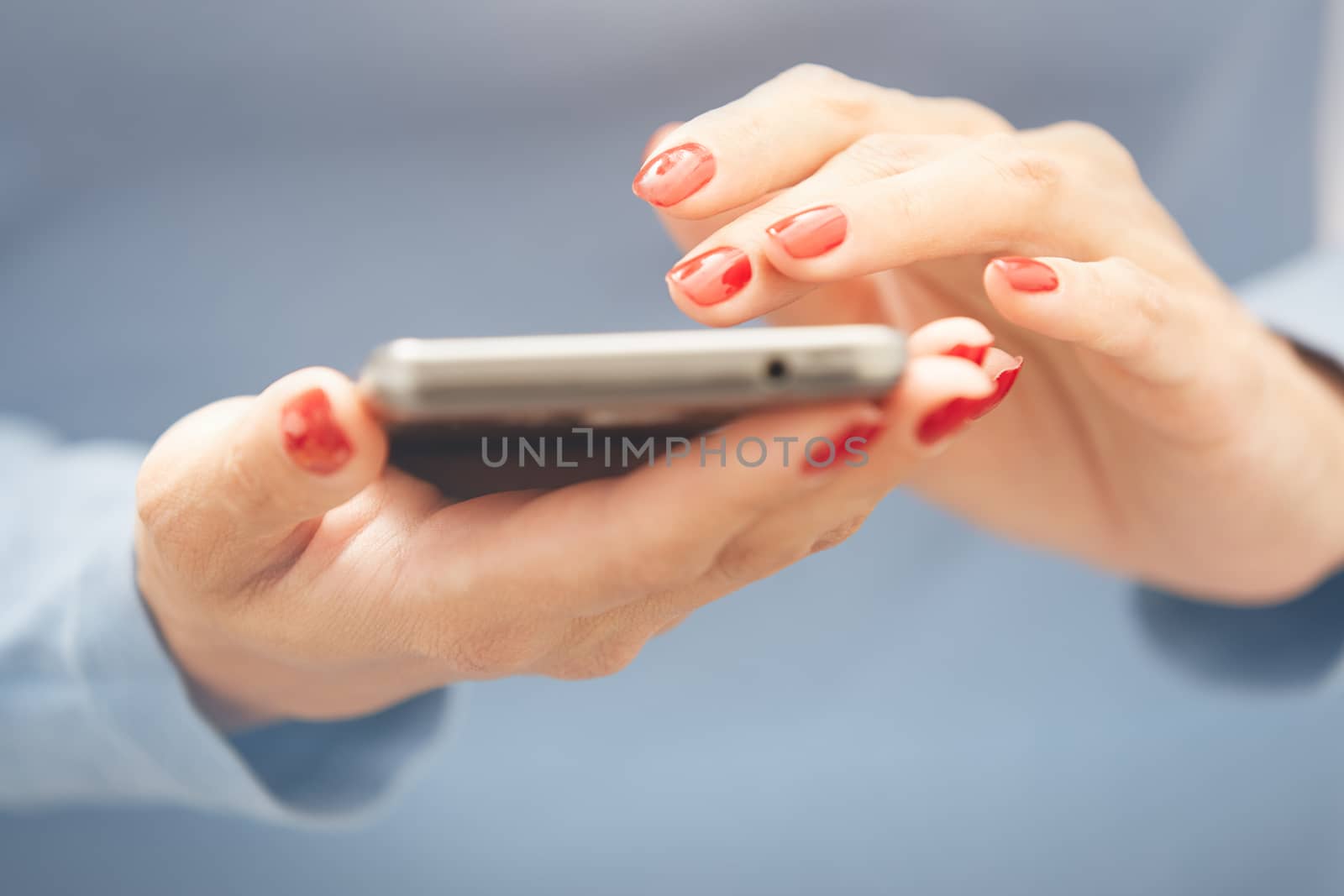 Woman with red manicure using smartphone. Horizontal photo