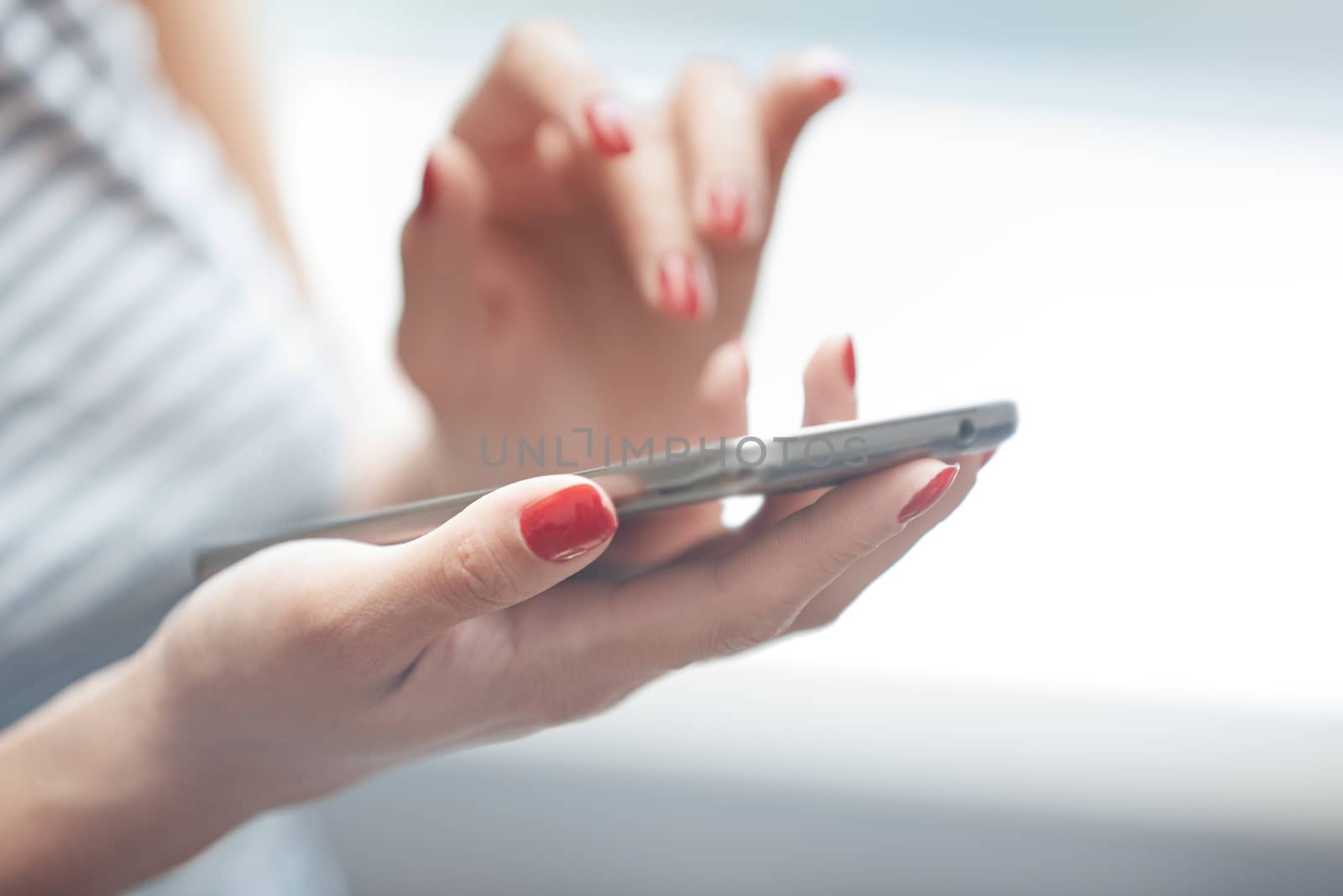 Woman with red manicure using smartphone. Horizontal photo