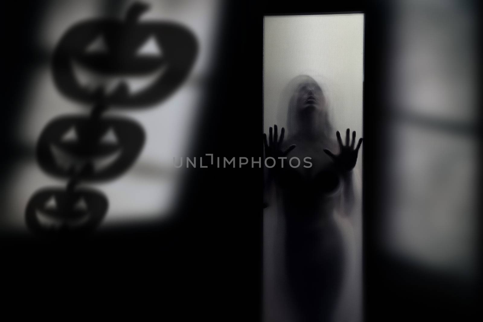 Silhouette of the woman behind the wall with Halloween pumpkin shades