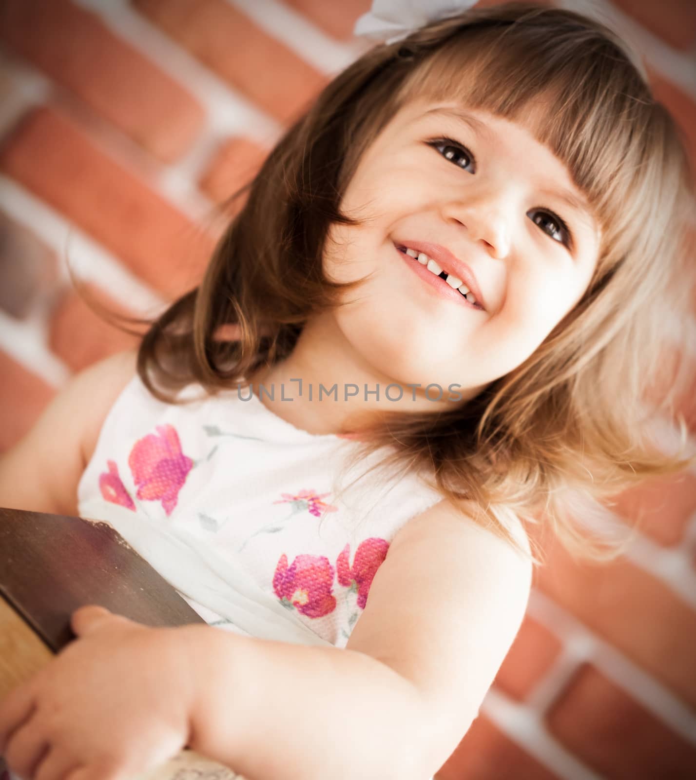 smiling little girl on a background of brick wall