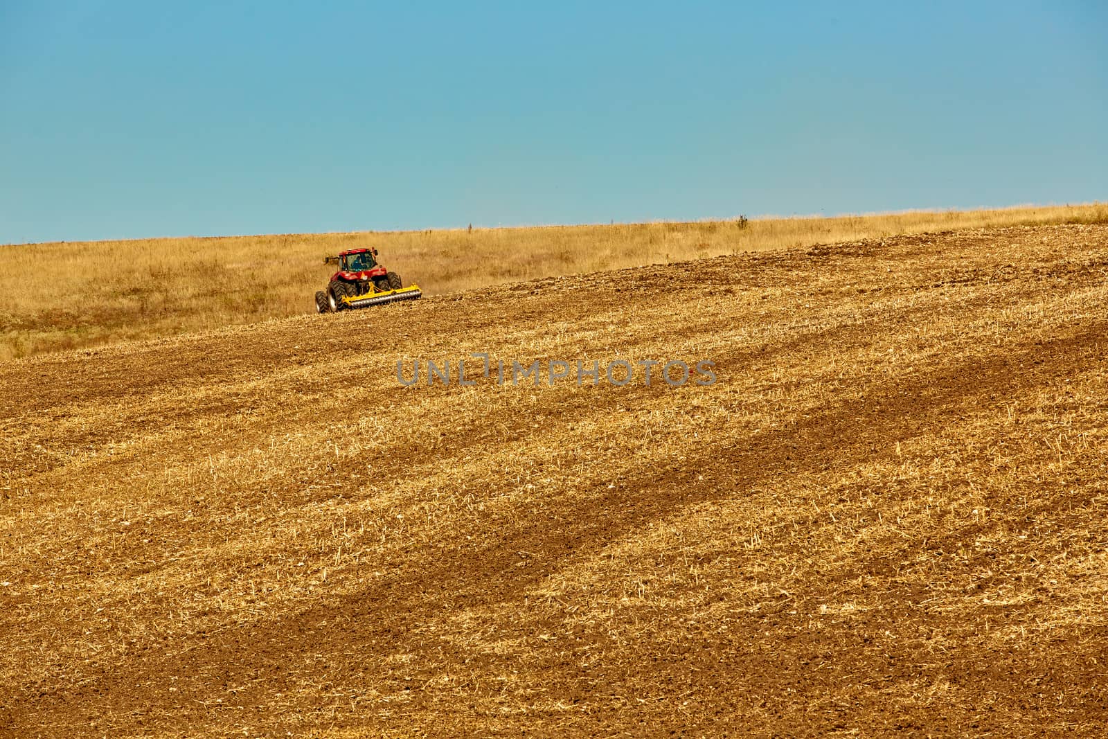 Agricultural Landscape. Tractor working on the field. Spring sunny day