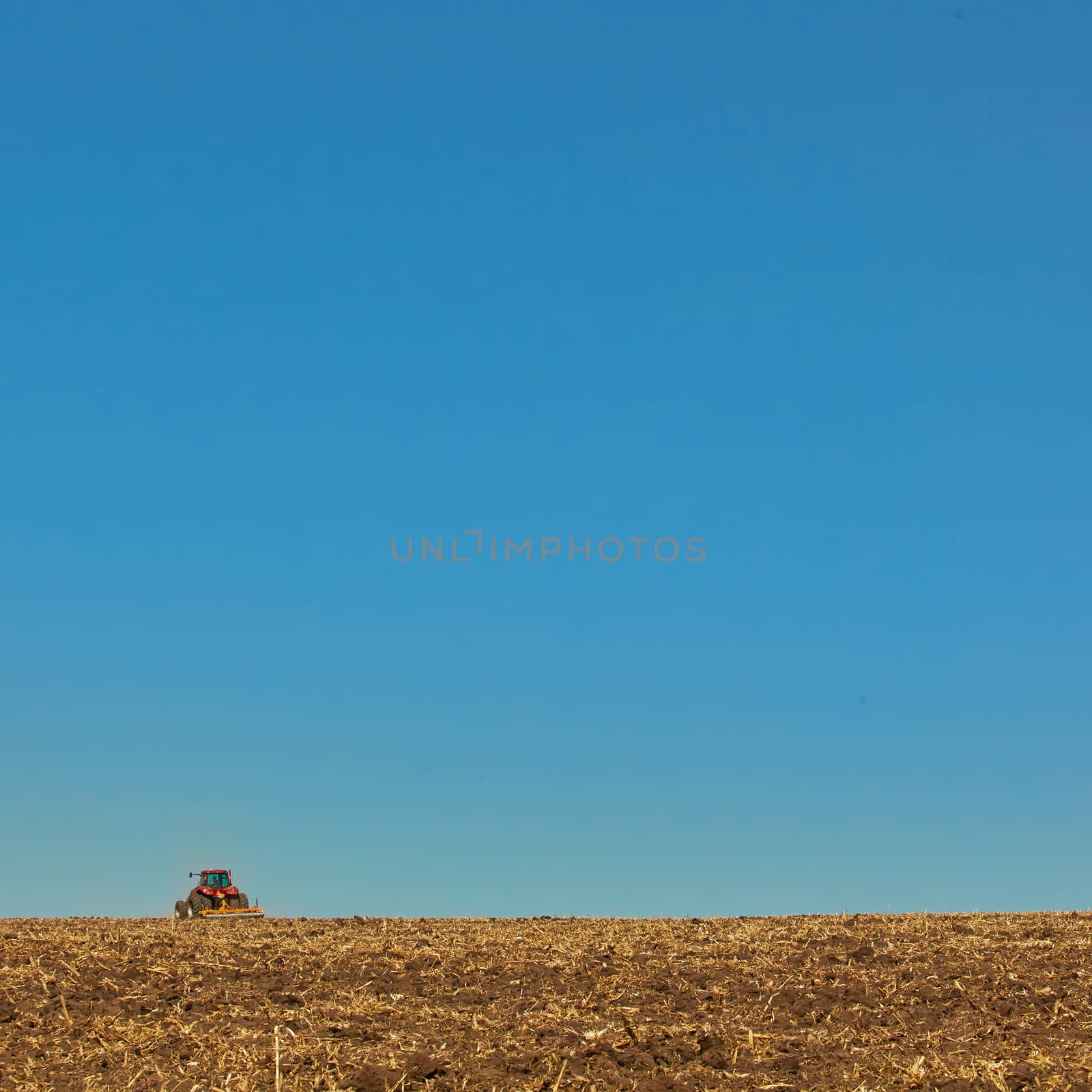 Agricultural Landscape. Tractor working on the field. Spring sunny day