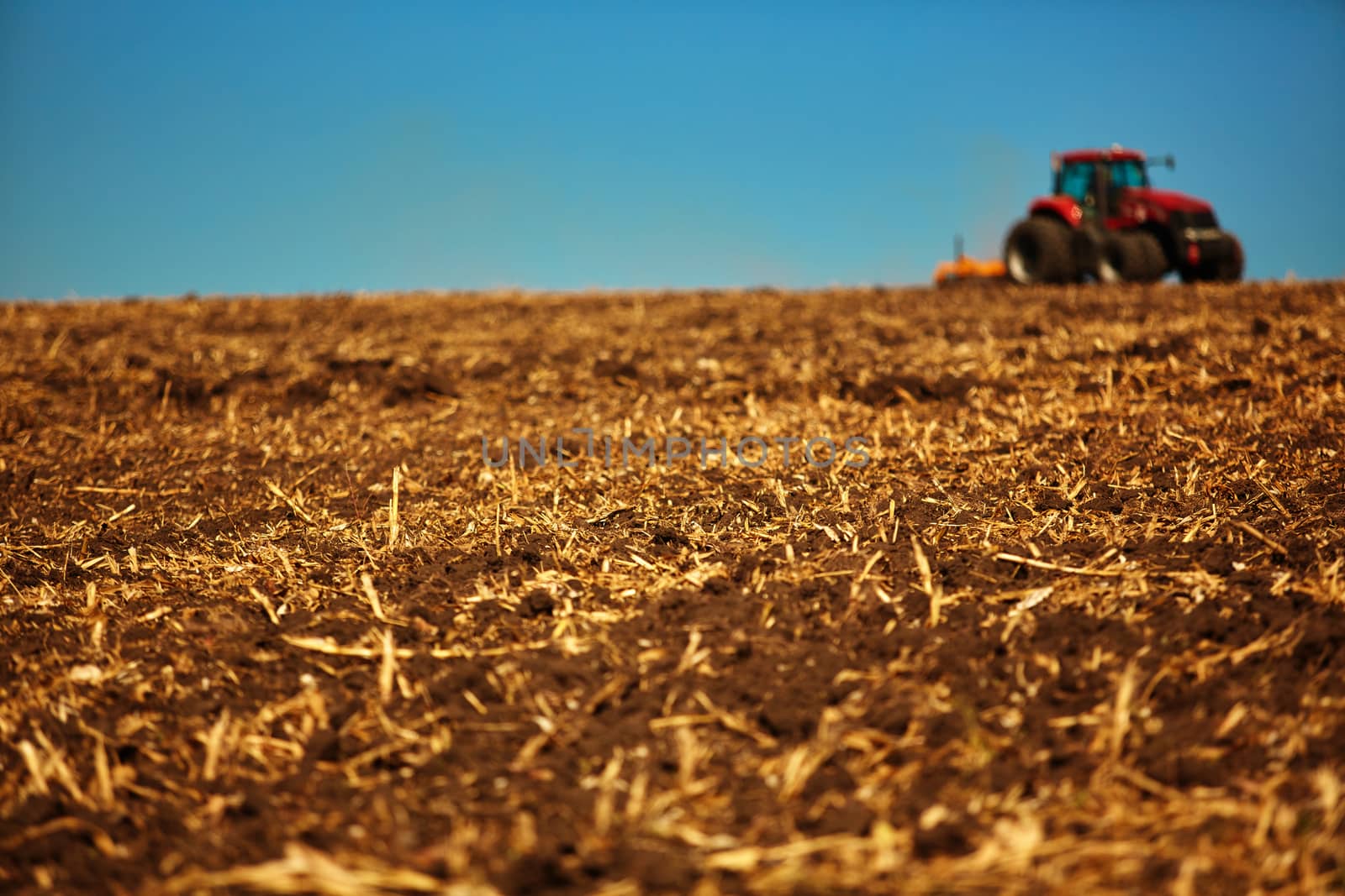 Agricultural Landscape. Tractor working on the field. Spring sunny day