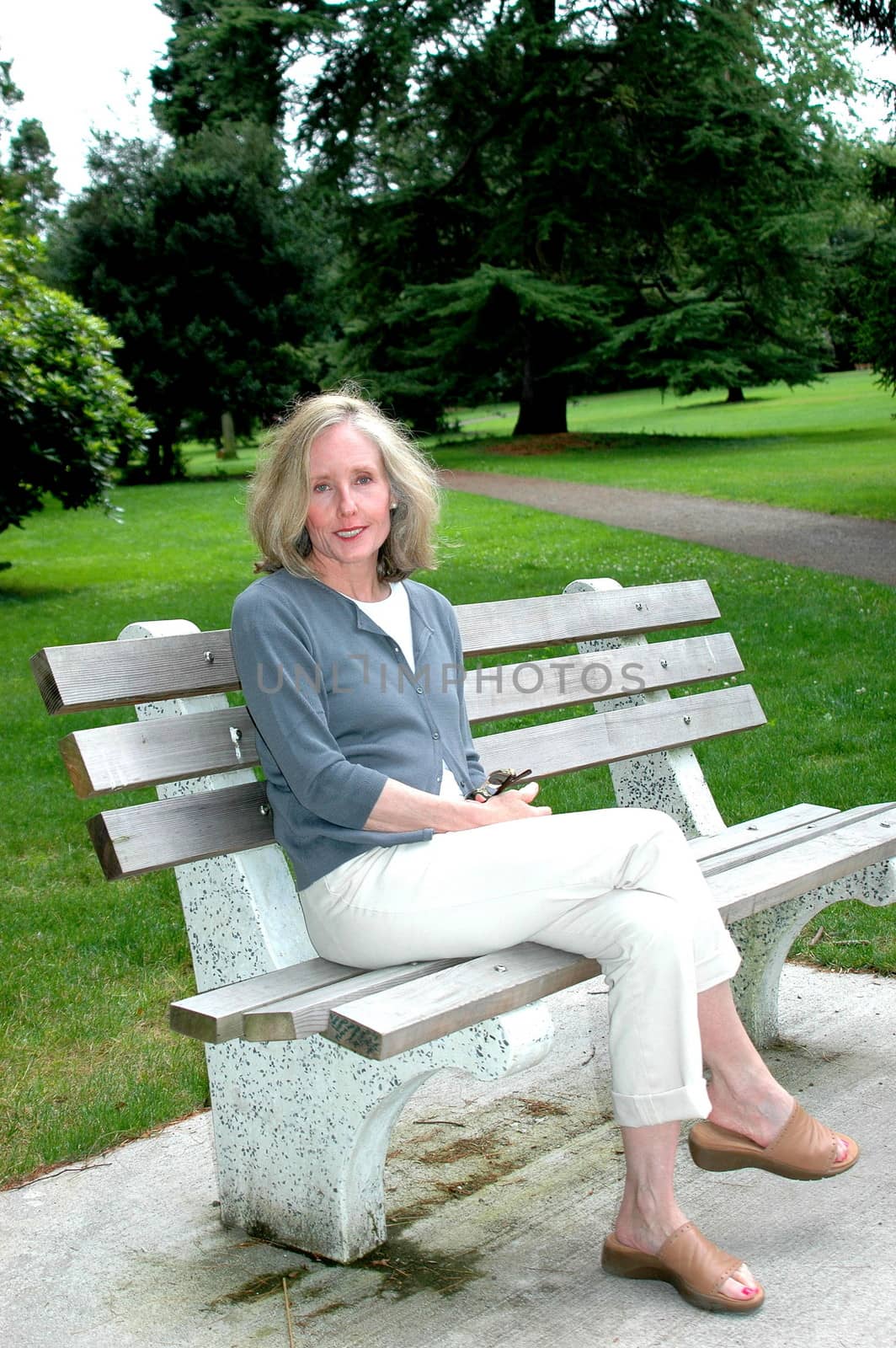 Mature female beauty relaxing on a park bench outdoors.
