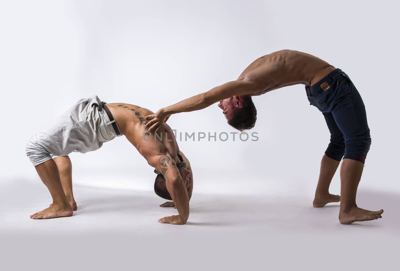 Muscular Shirtless Male Acrobatic Dancers Balancing on Top of Each Other in Studio with White Background