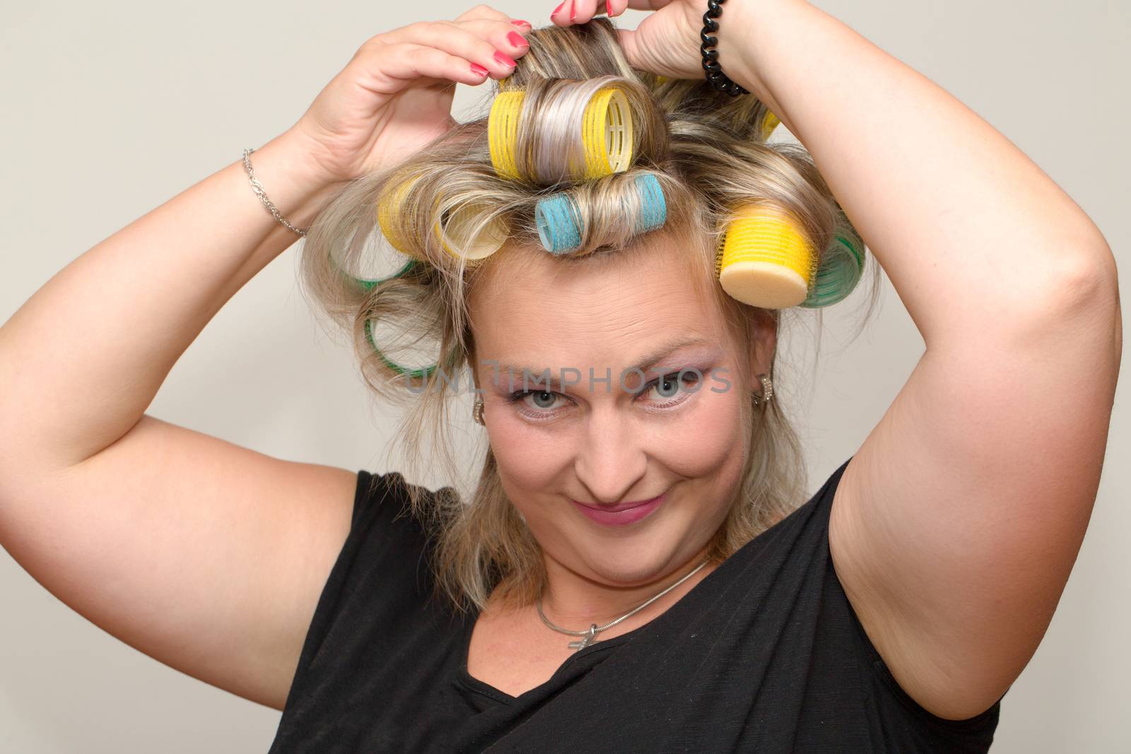 portrait of beautiful plus size young blond woman posing with home with curlers
