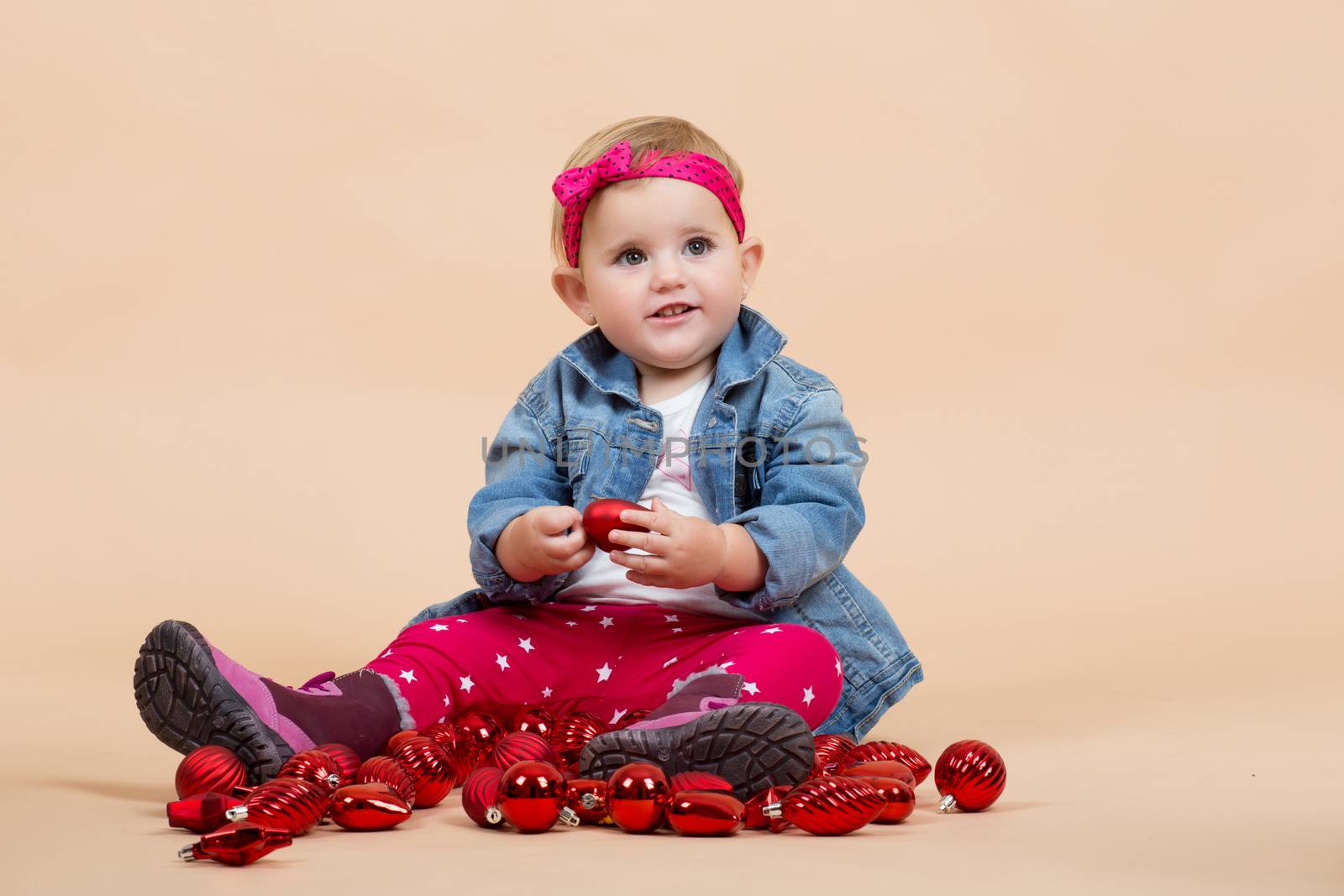 portrait of young cute baby on beige background with christmas balls