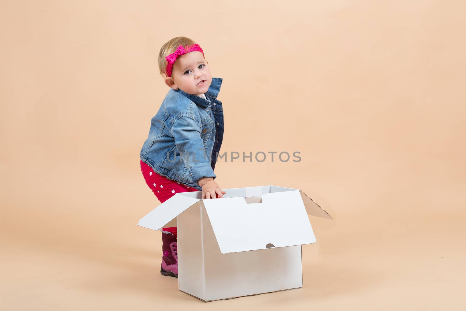 portrait of young cute baby on beige background with white paper box
