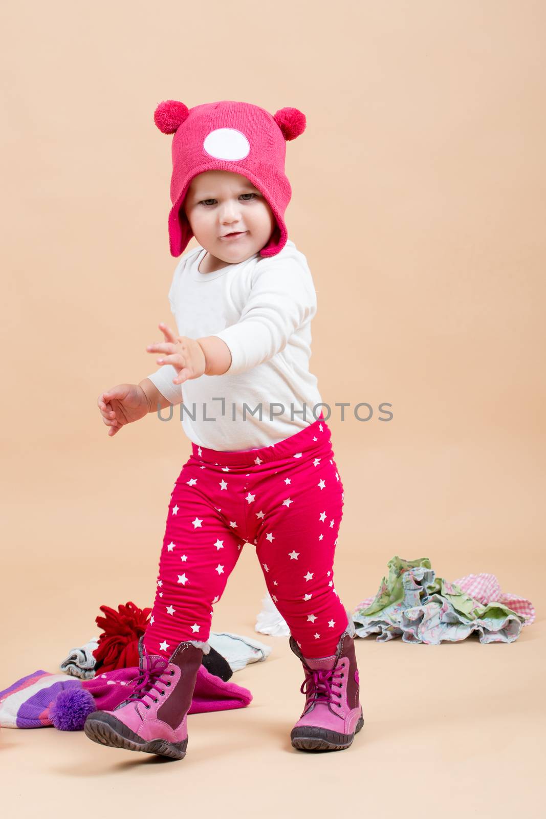 portrait of young cute baby with funny cap on head on beige background