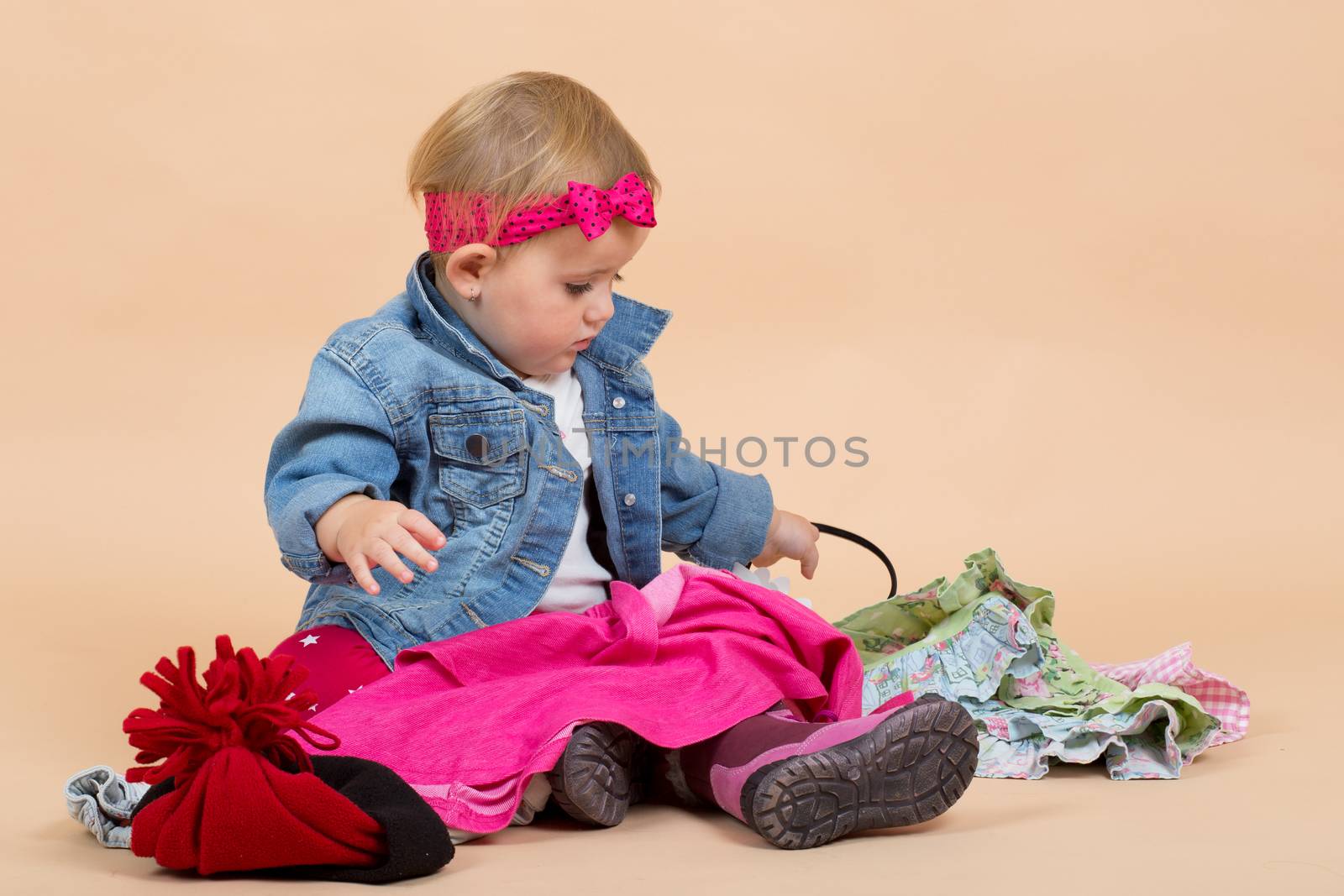 portrait of young cute baby on beige background checking winter clothing