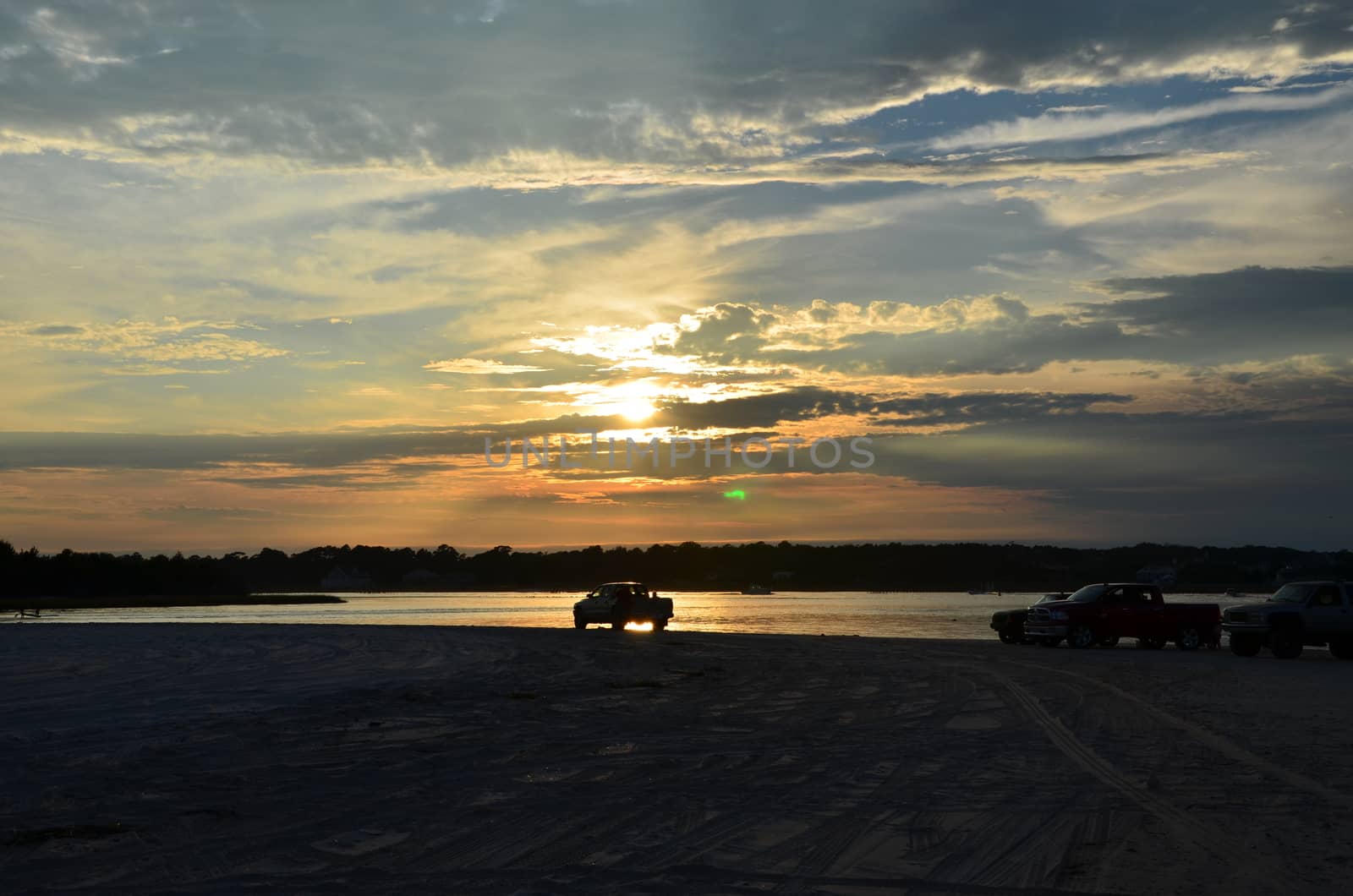 The north end of Carolina Beach at sunset, with a car parked near the water