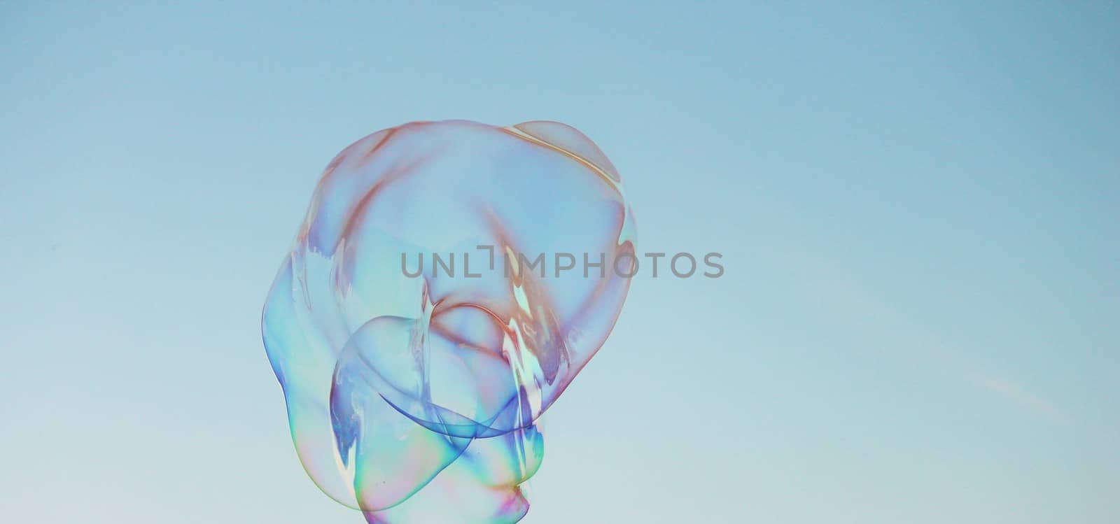 Soap bubbles on a blue sky illuminated by the sun by cheekylorns