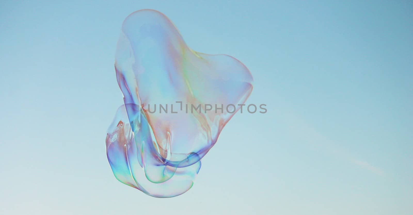 Soap bubbles on a blue sky illuminated by the sun by cheekylorns
