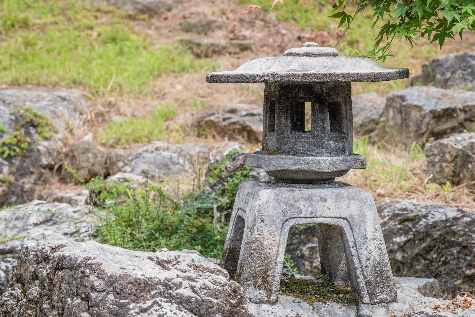 An old traditional Japanese stone lantern in a Japanese home garden.