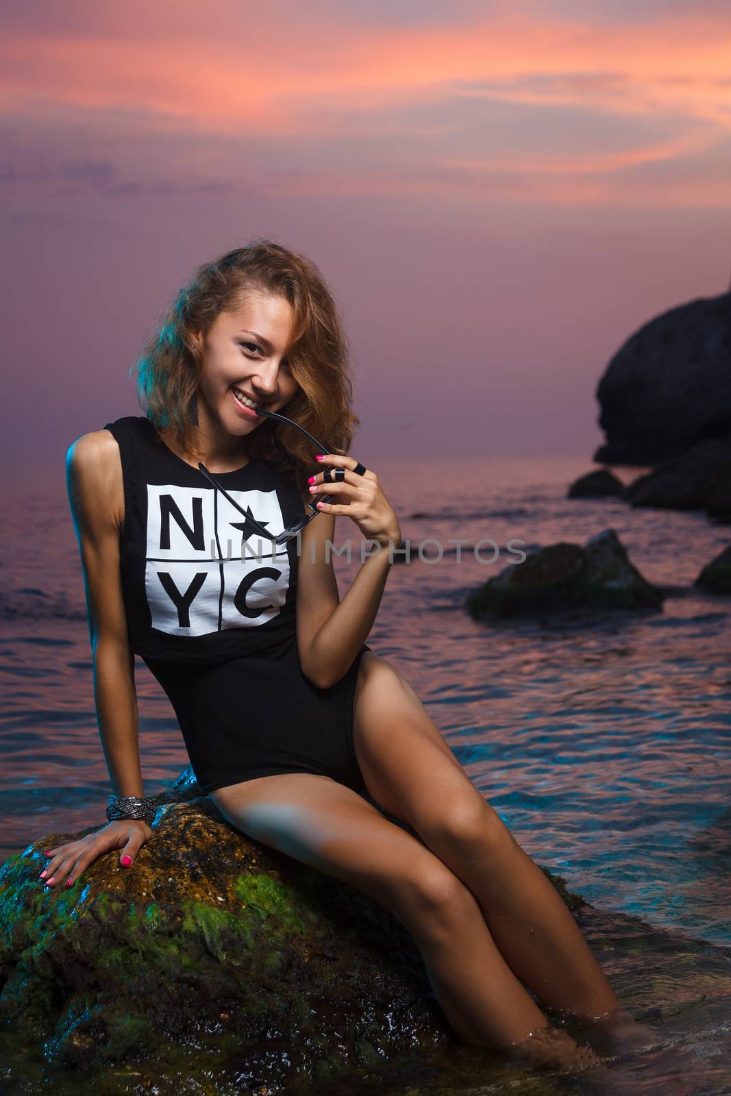 Teen girl sitting on stone fashion shoot at sunset beach by mrakor