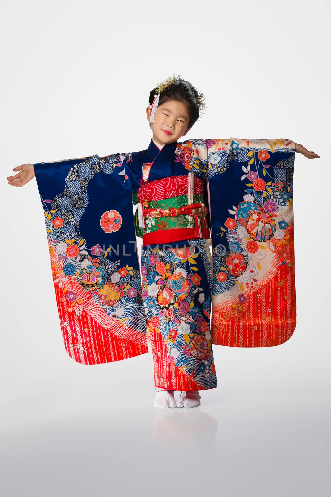 A cute young Japanese girl wearing a Kimono on a white background.