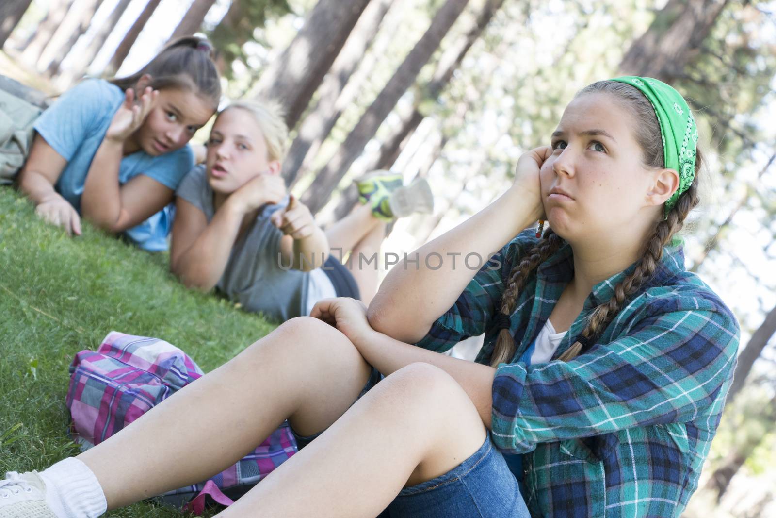 Two Young Girls Gossiping about another Girl