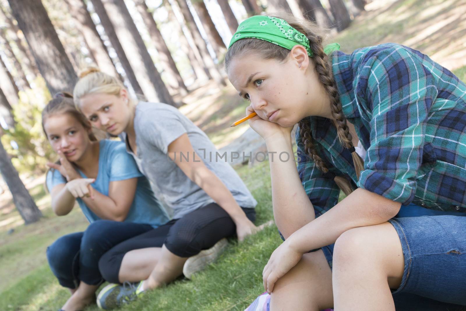 Two Young Girls Gossiping about another Girl