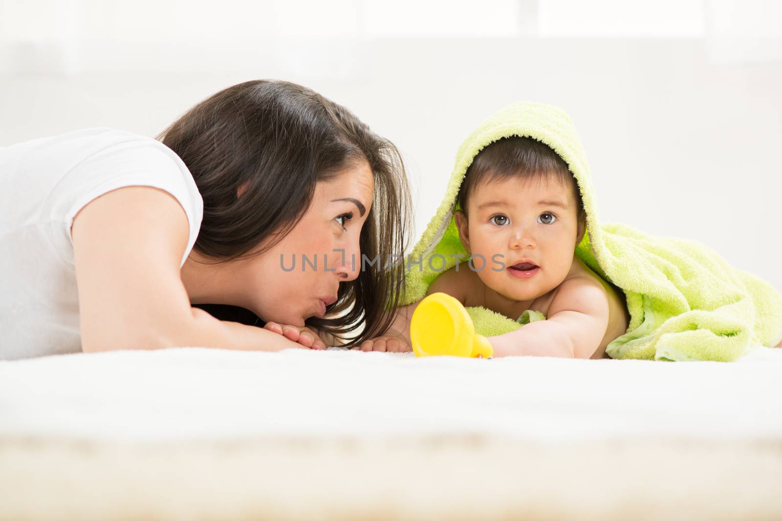 Mother and baby lying and playing after bathing