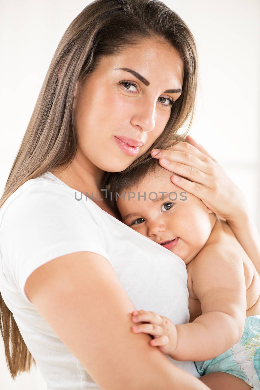 Beautiful Mother holding her baby boy. Looking at camera.