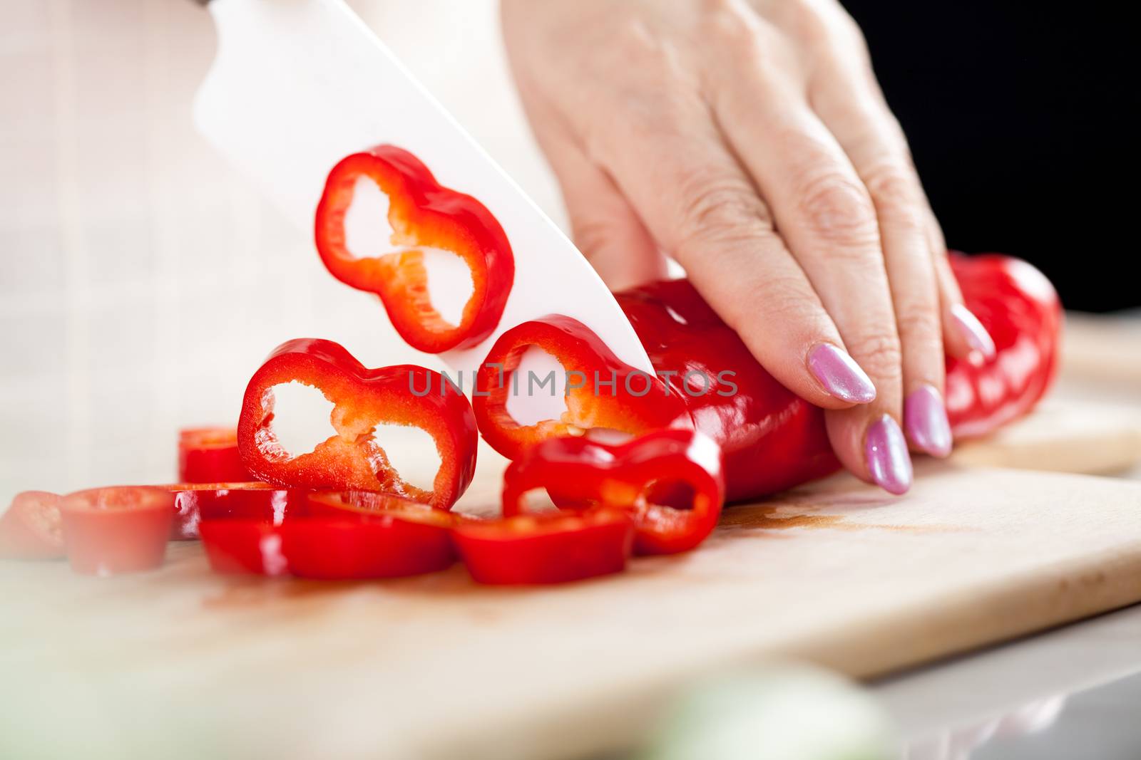 Senior female Hands Cutting red peppers on the kitchen board.