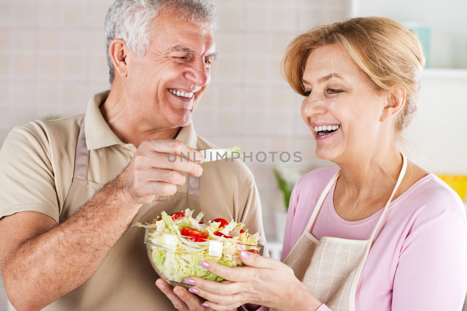 Senior Couple eating salad in the kitchen.