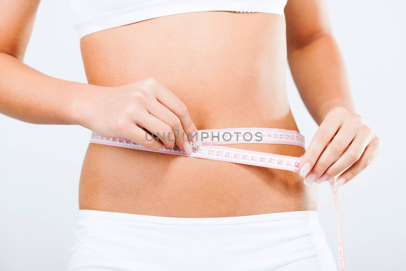 Young woman measuring perfect shape of waist