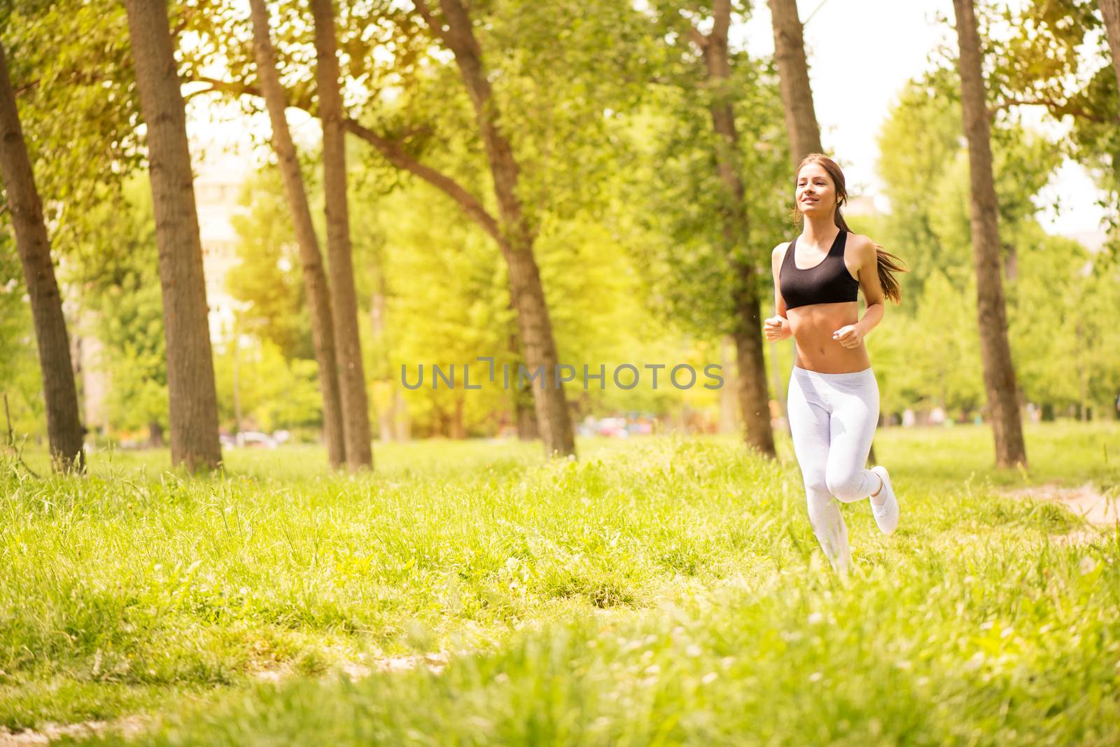 Happy young beautiful woman running in the park