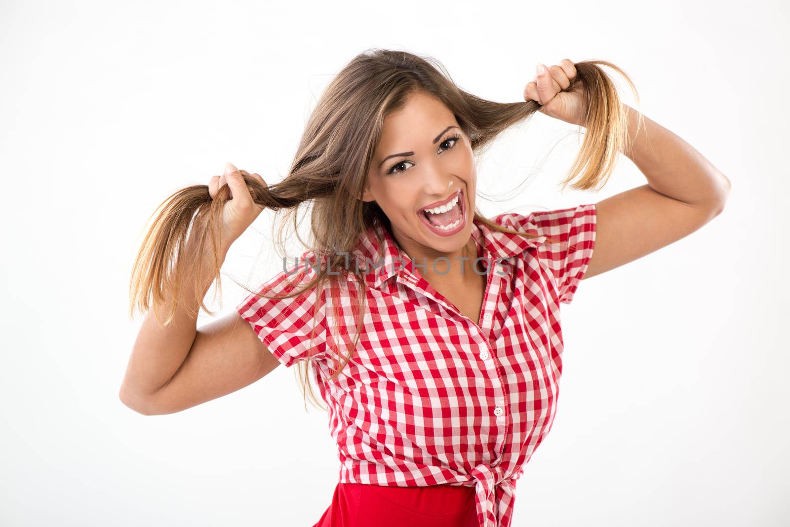 Beautiful young woman having fun. She is holding her hair in a two ponytail and looking at camera.