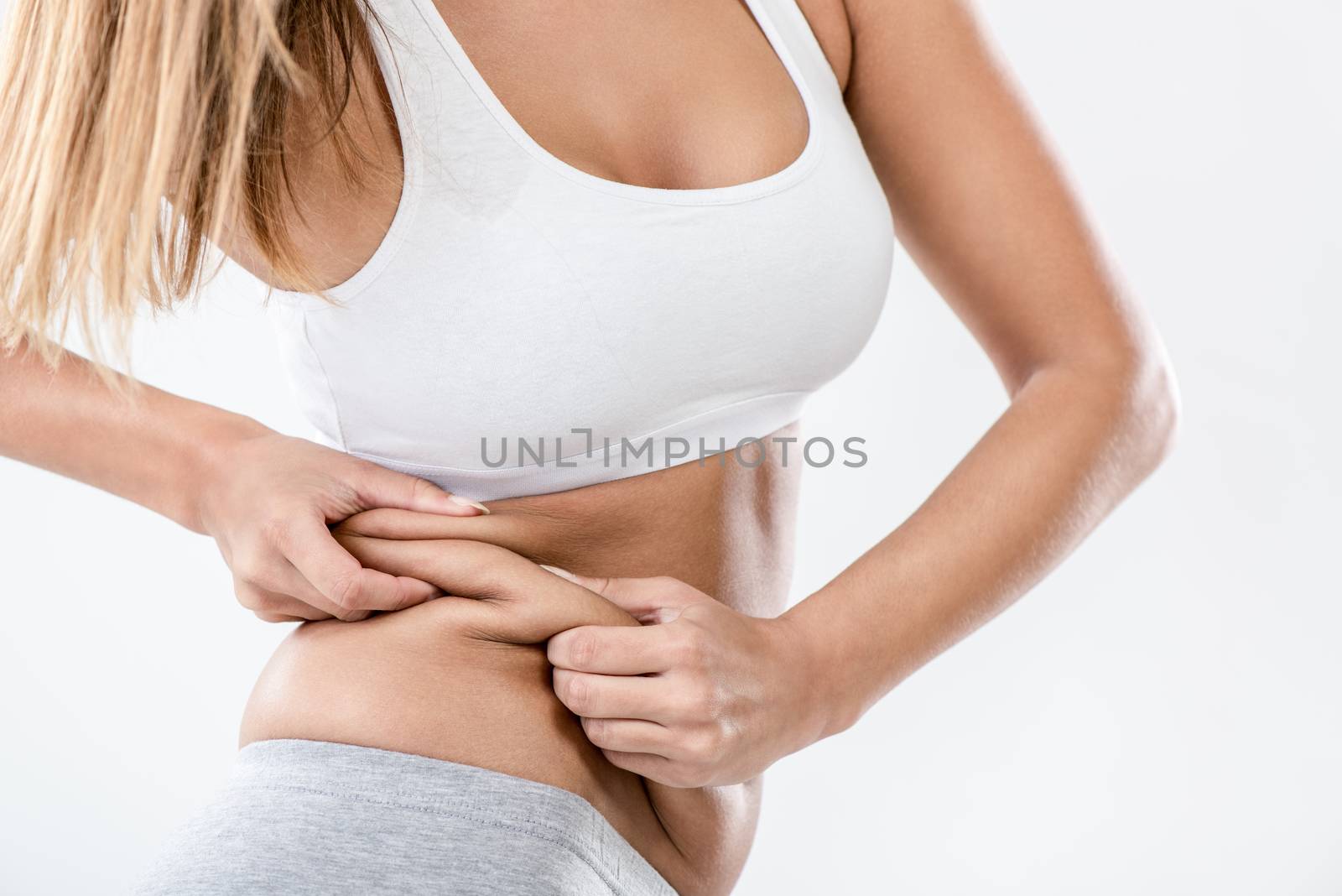 Woman pinching waist and checking her body fat. Close-up.