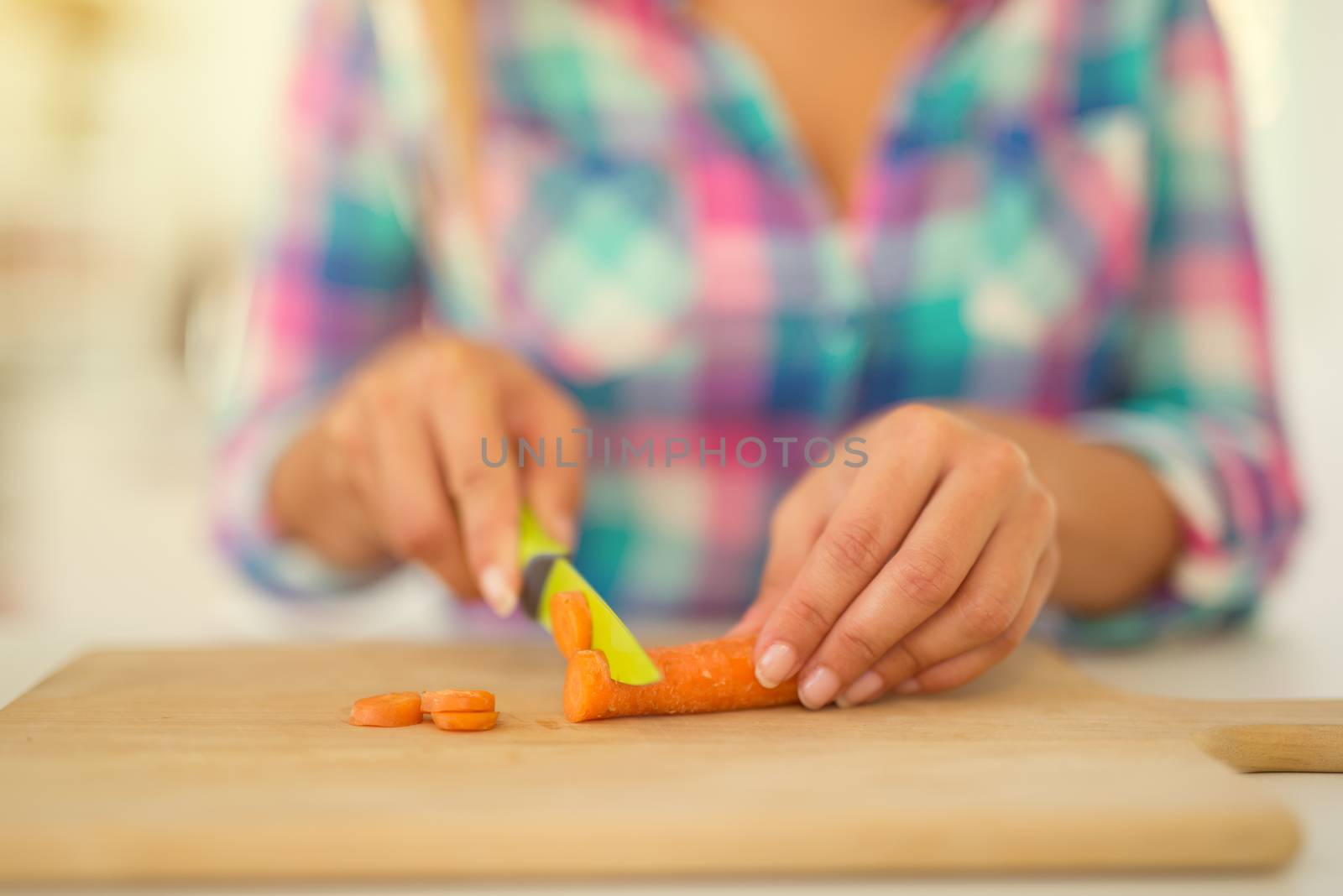 Close-up of a female Hands cutting carrot on the kitchen board.