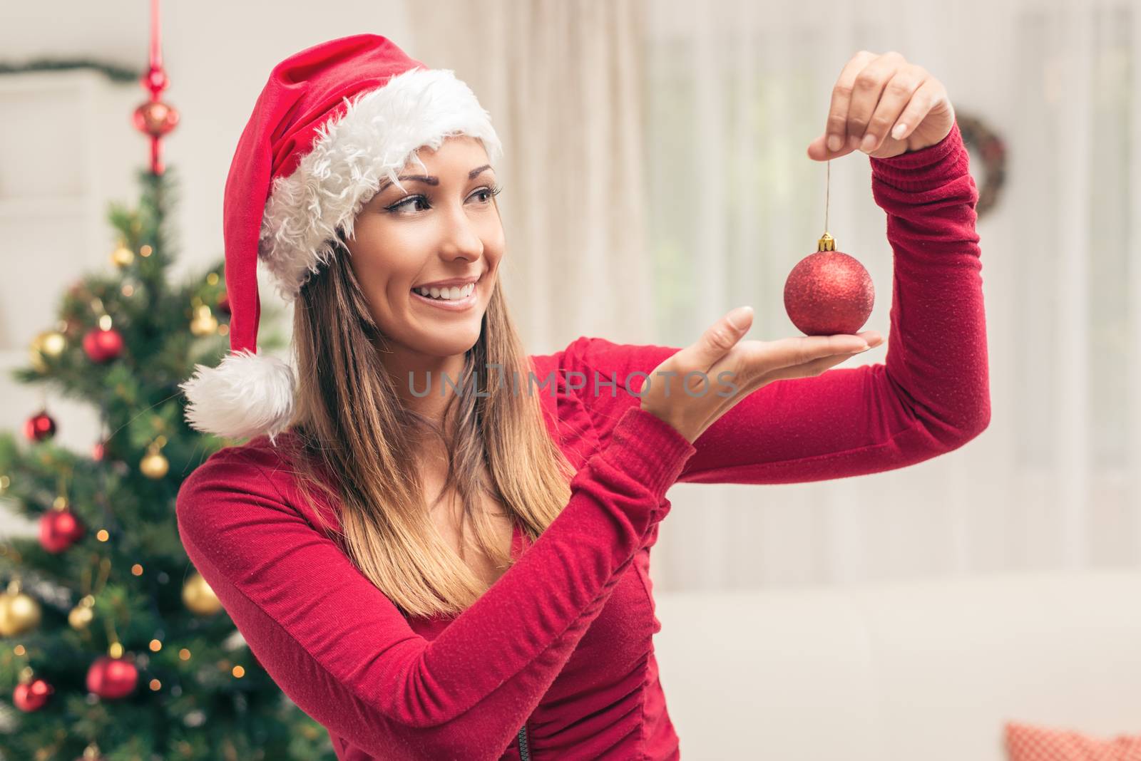 Happy beautiful young woman holding red Christmas ornament