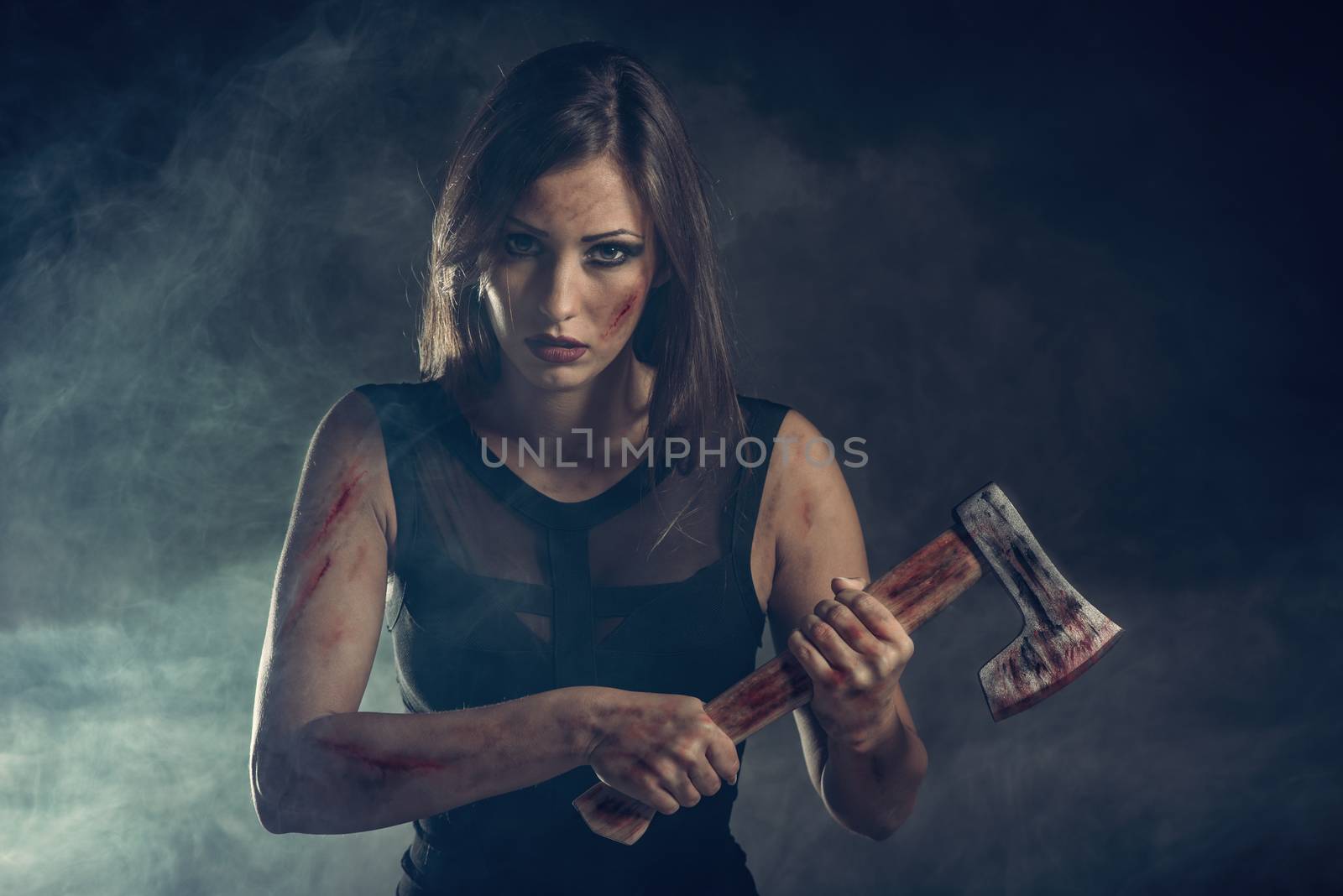 Beautiful dangerous girl with rusty axe. Looking at camera.