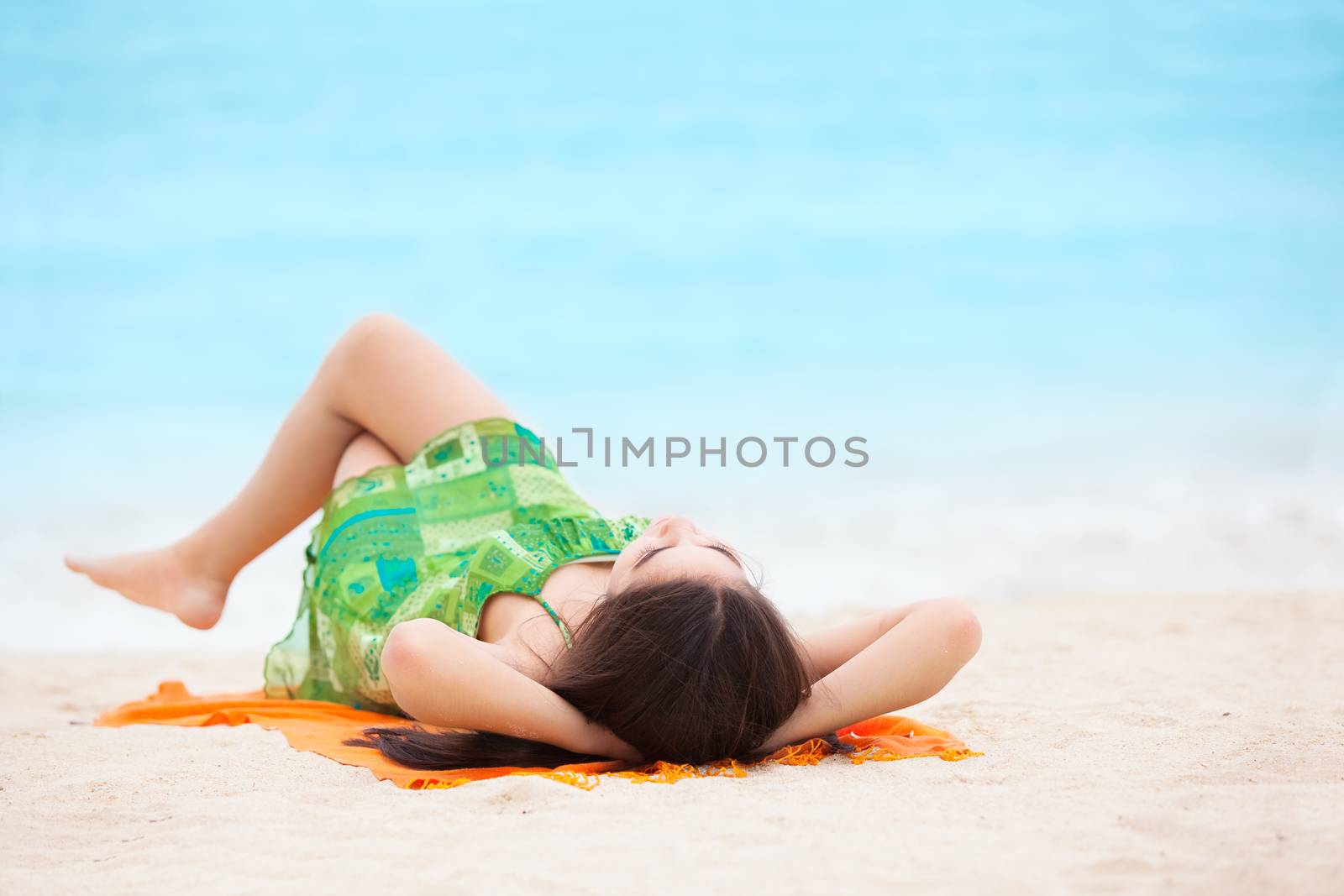 Biracial teen girl arms lying on beach relaxing by ocean water  by jarenwicklund