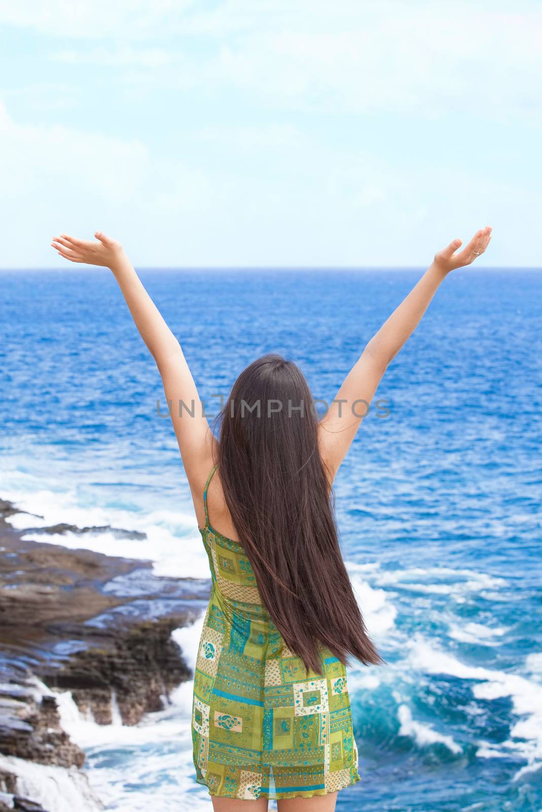 Biracial teen girl arms raised by ocean water in praise by jarenwicklund