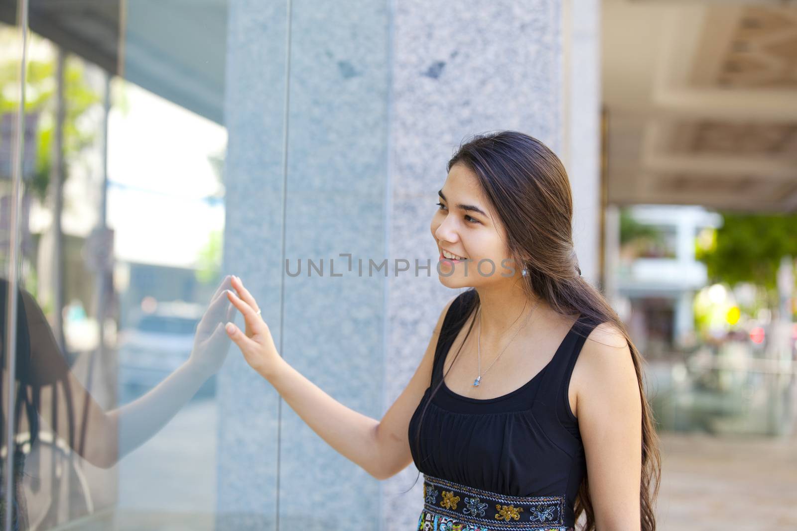 Biracial teen girl window shopping, looking into store front gla by jarenwicklund