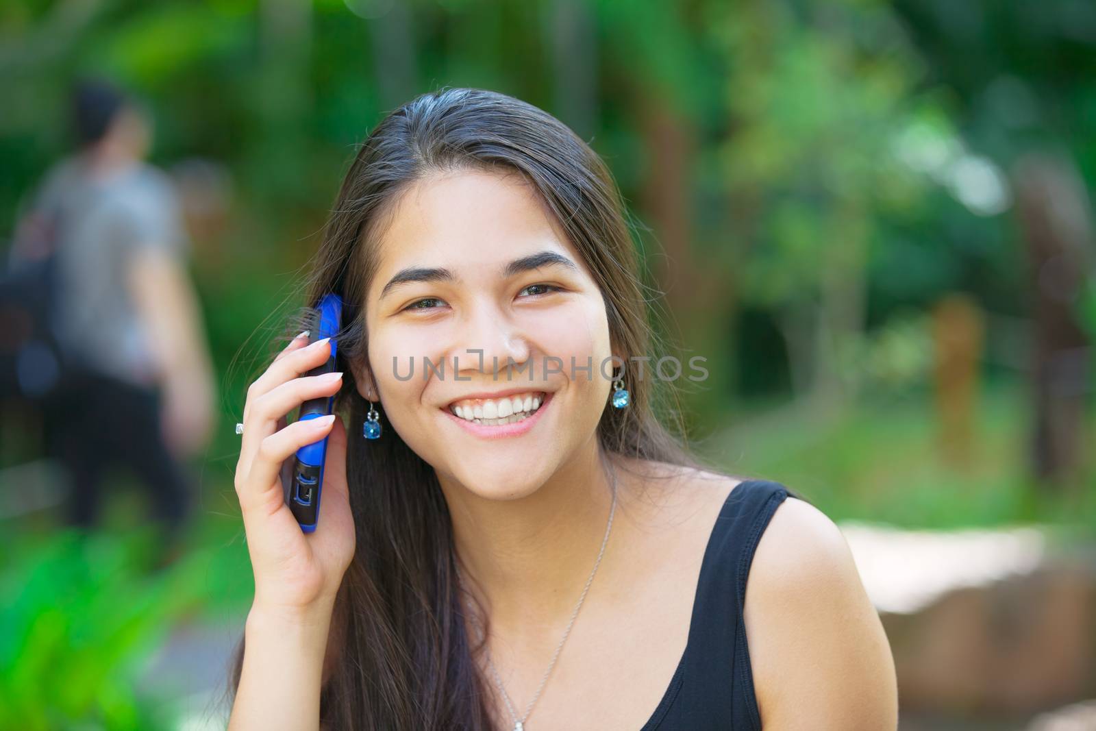 Biracial teen girl talking on cell phone outdoors by jarenwicklund