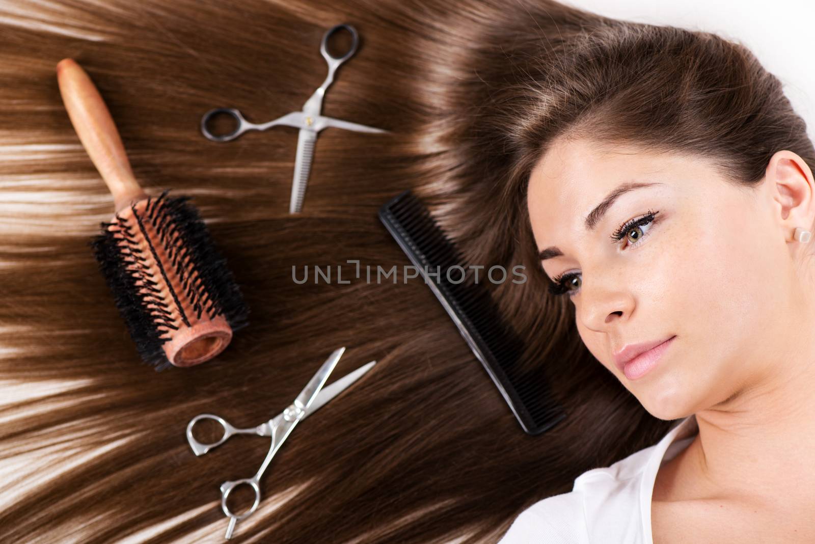 Cute young woman with Beautiful healthy shiny hair and Haircutting Equipment.