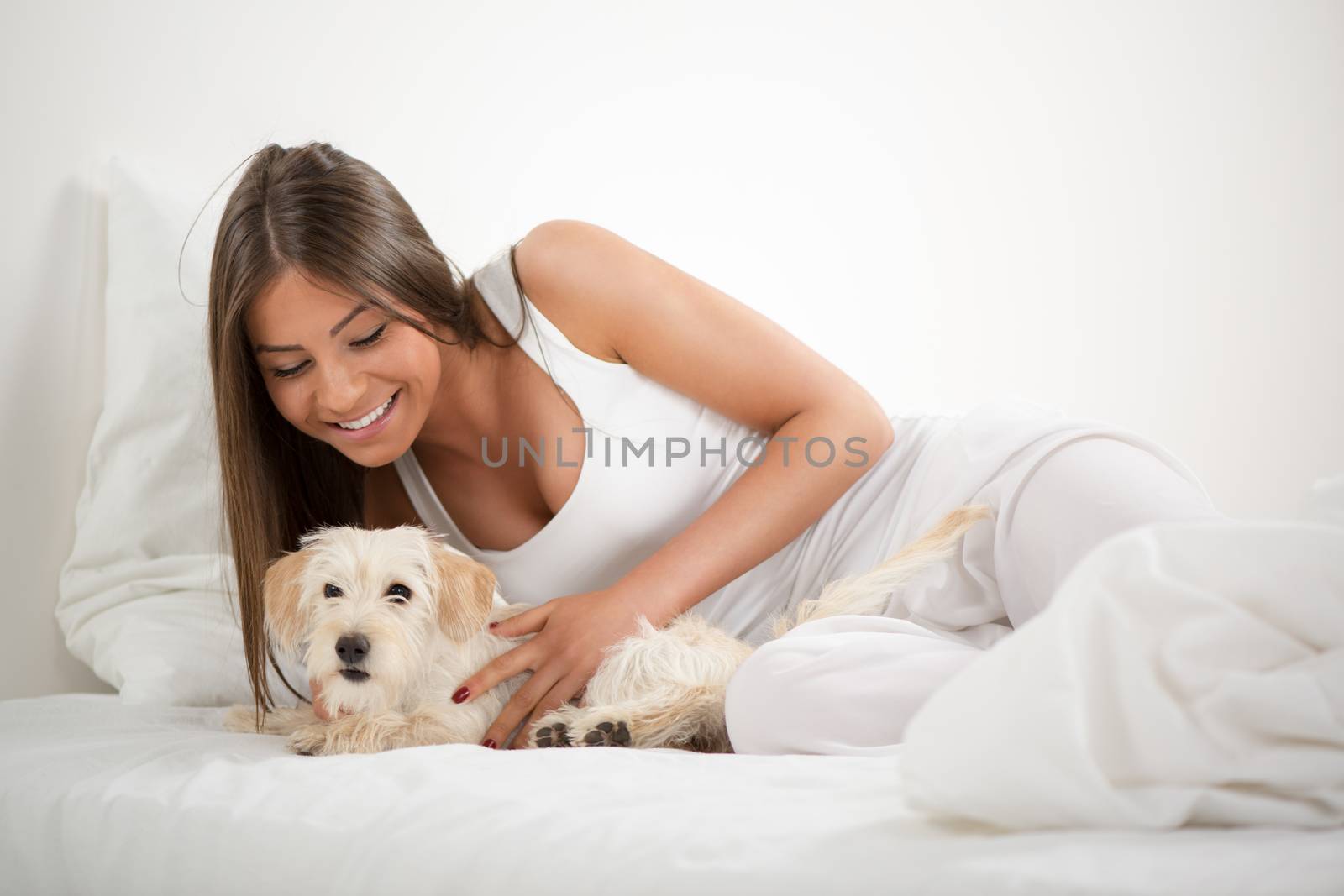 Young beautiful woman and her dog resting in bed