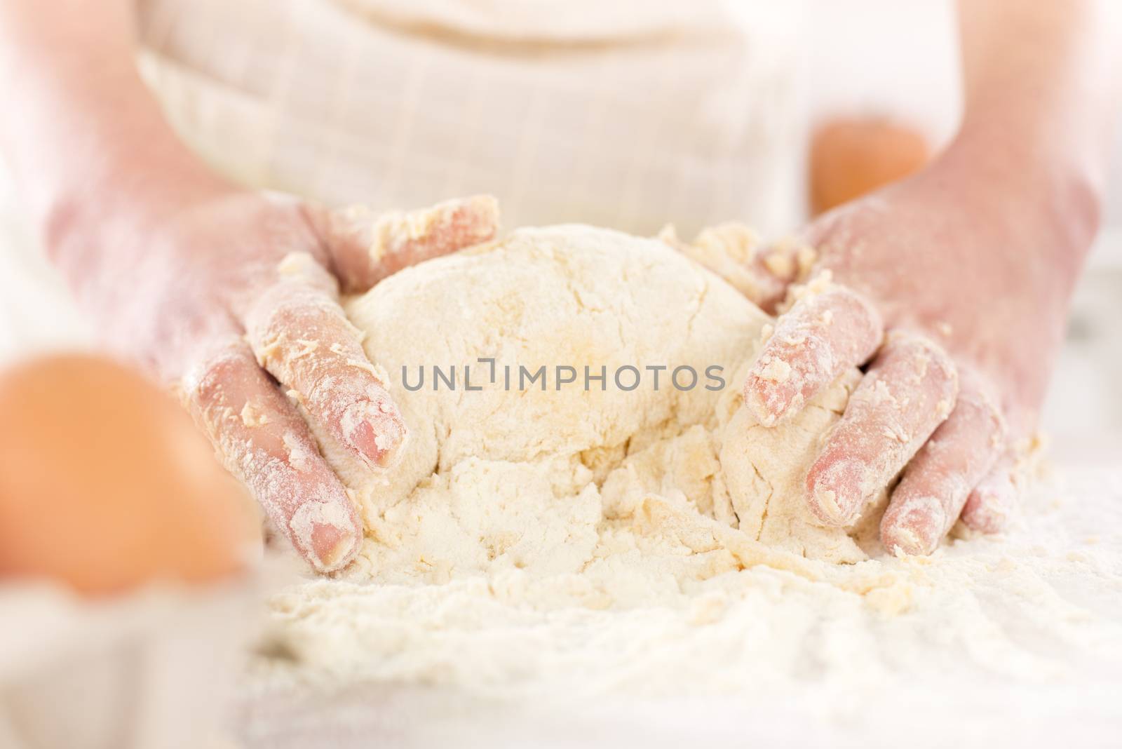 Pair of woman's hands kneading dough on table. Close-up