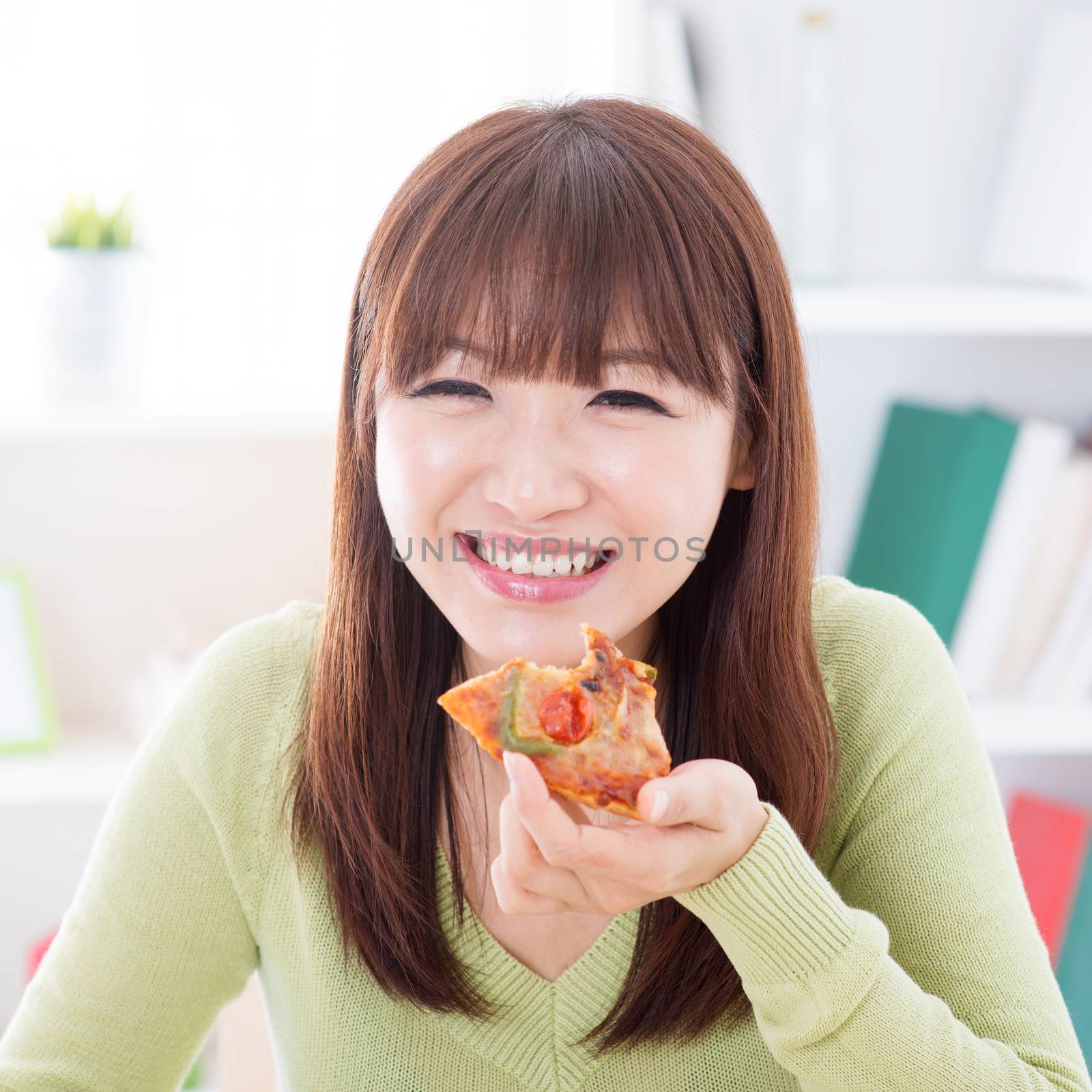 Asian female eating pizza at home. Woman living lifestyle indoors.