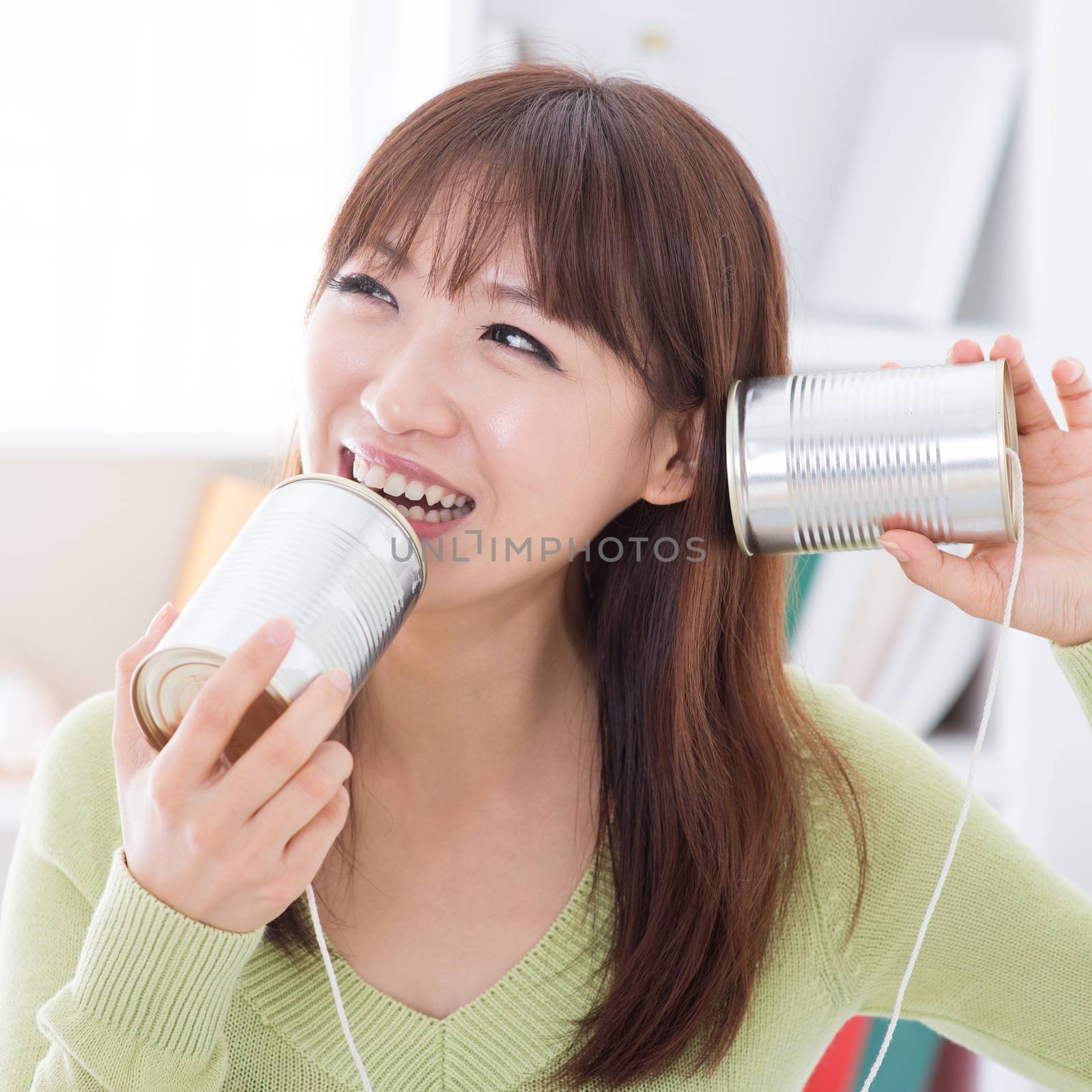 Asian girl using old technology, talk and listen to communication cans. Young woman indoors living lifestyle at home.