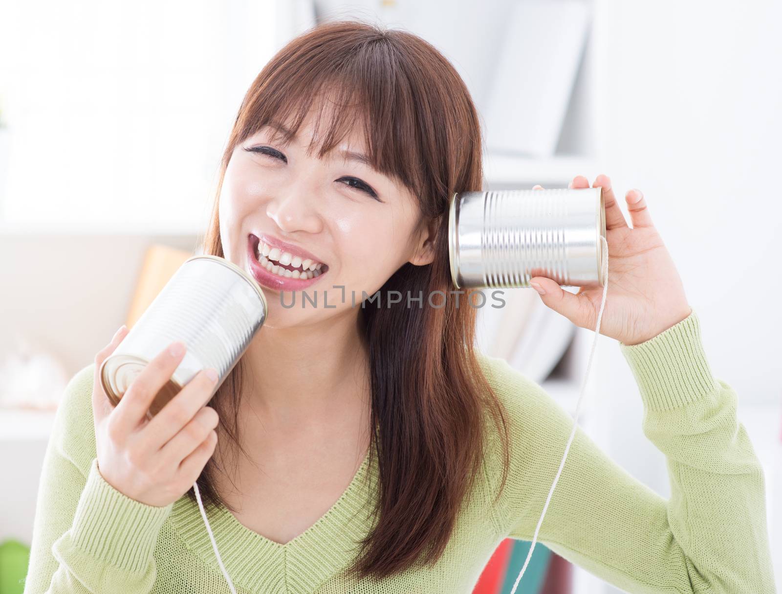 Happy Asian girl using old technology, talk and listen to communication cans. Young woman indoors living lifestyle at home.