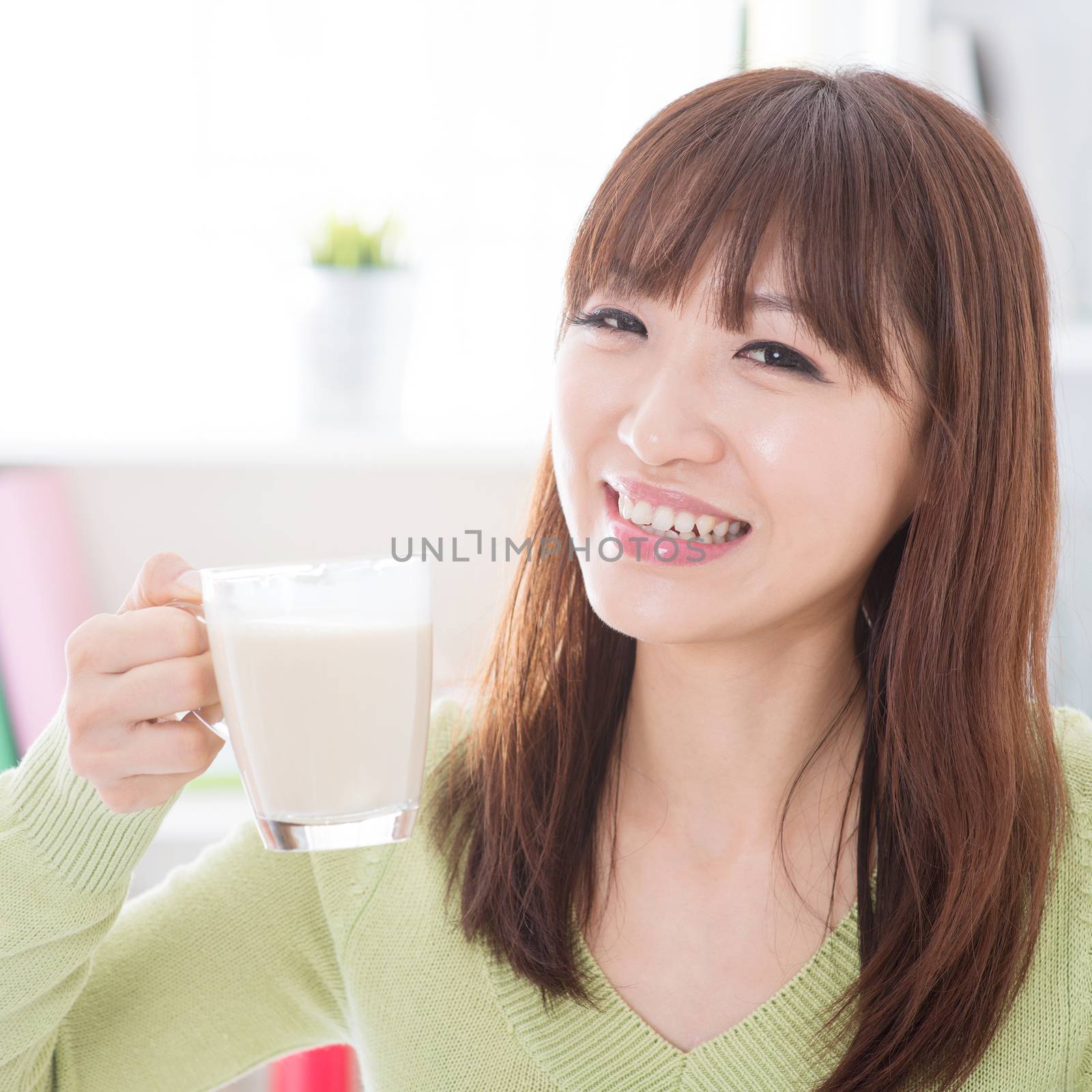 Portrait of happy Asian girl drinking dairy milk as breakfast. Young woman indoors living lifestyle at home.
