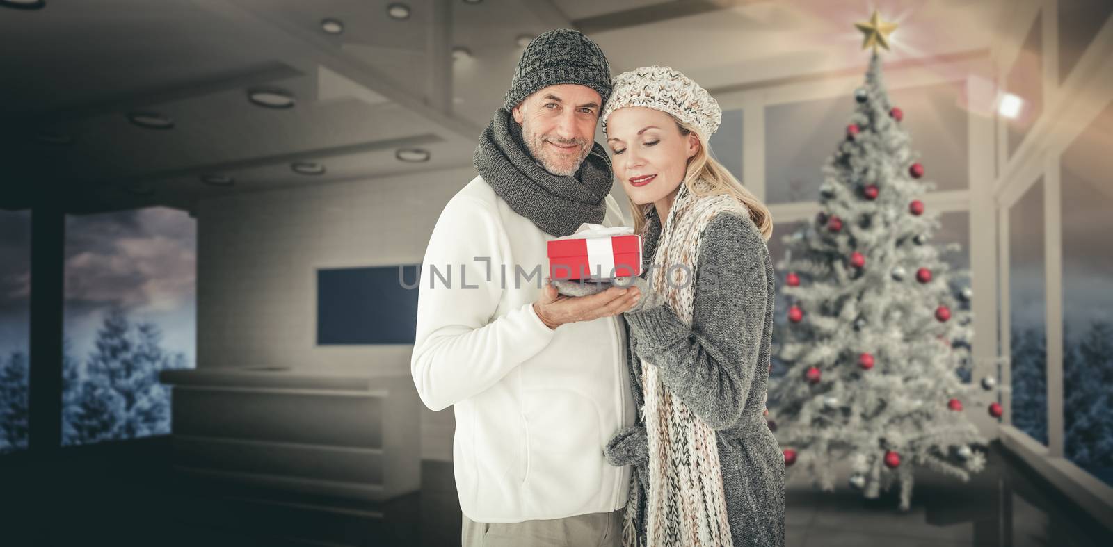 Composite image of happy winter couple with gift by Wavebreakmedia