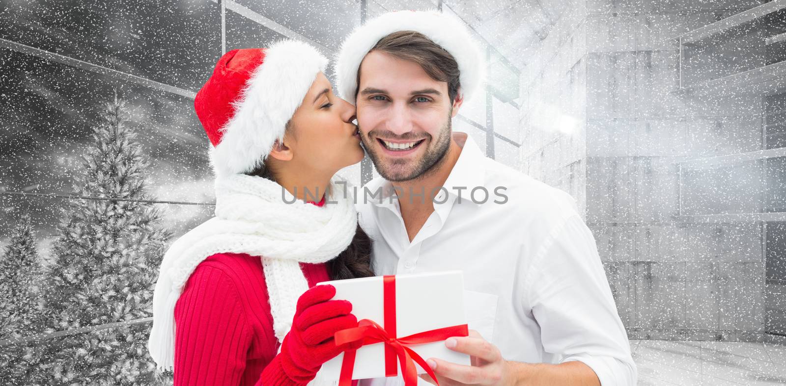 Festive young couple holding gift against window overlooking snowy forest